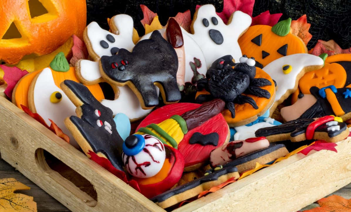 Halloween Treats 桌布 壁紙 — 一個木托盤上放滿了色彩繽紛的萬聖節糖餅乾，形狀有鬼魂、南瓜、蝙蝠、蜘蛛和眼珠。