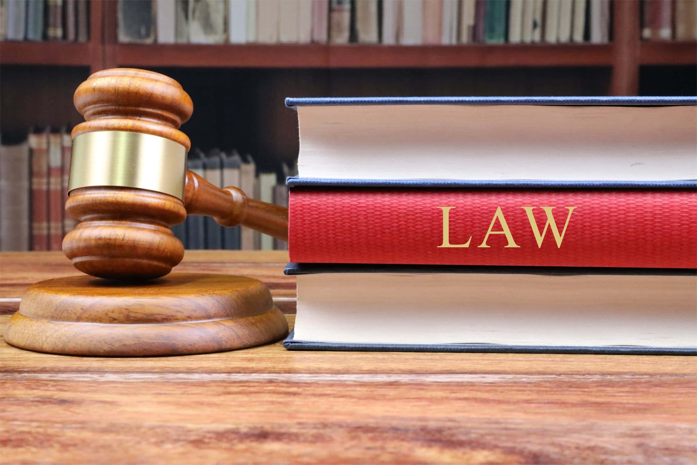 Law 桌布 壁紙 — 一個木槌放在一堆法律書籍旁邊，放在一張拋光的桌子上，背景有書架。