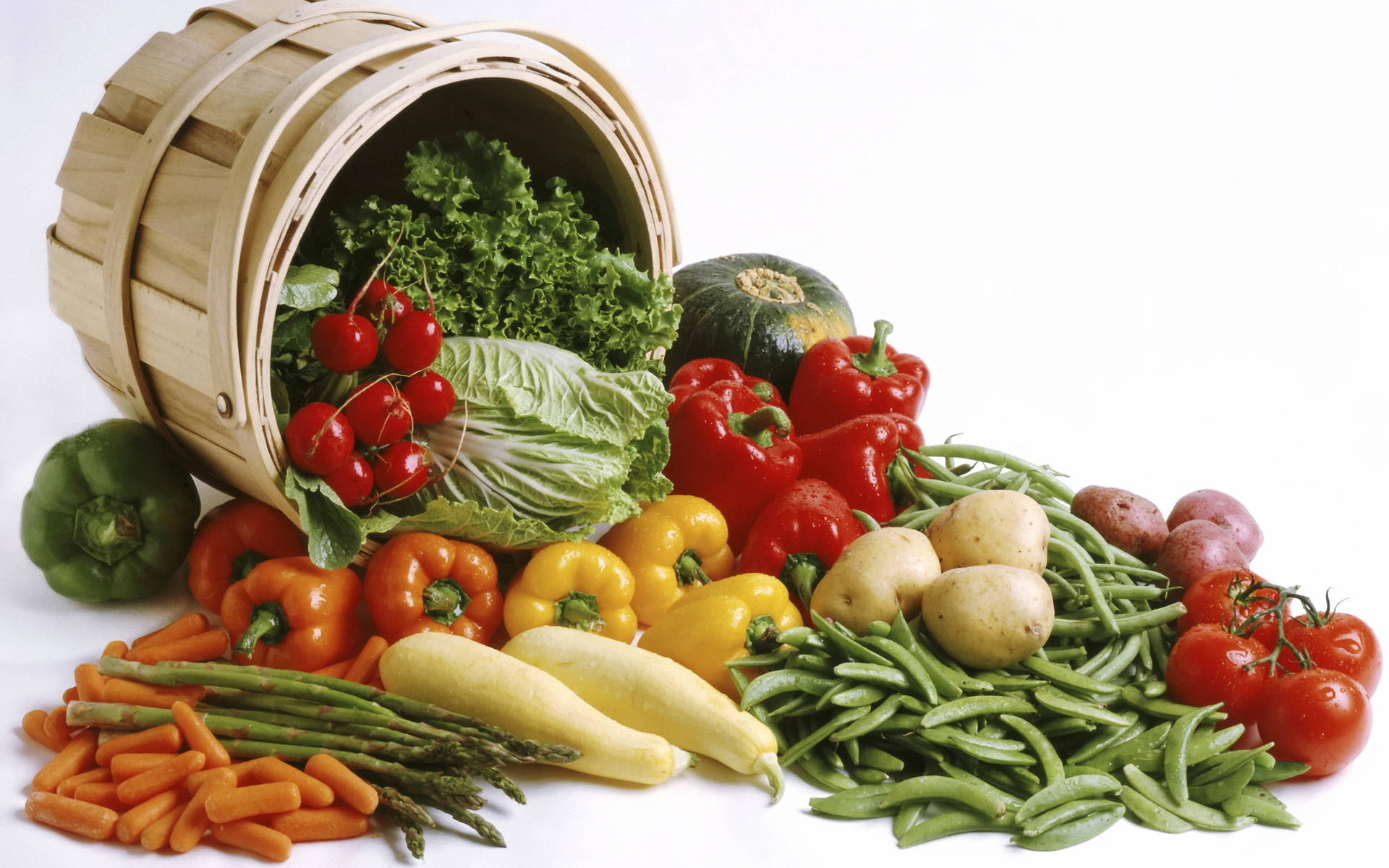 Vegetable 桌布 壁紙 — 一個木籃子溢出色彩鮮豔的新鮮蔬菜，包括番茄、甜椒、紅蘿蔔和豆類，背景是乾淨的白色。