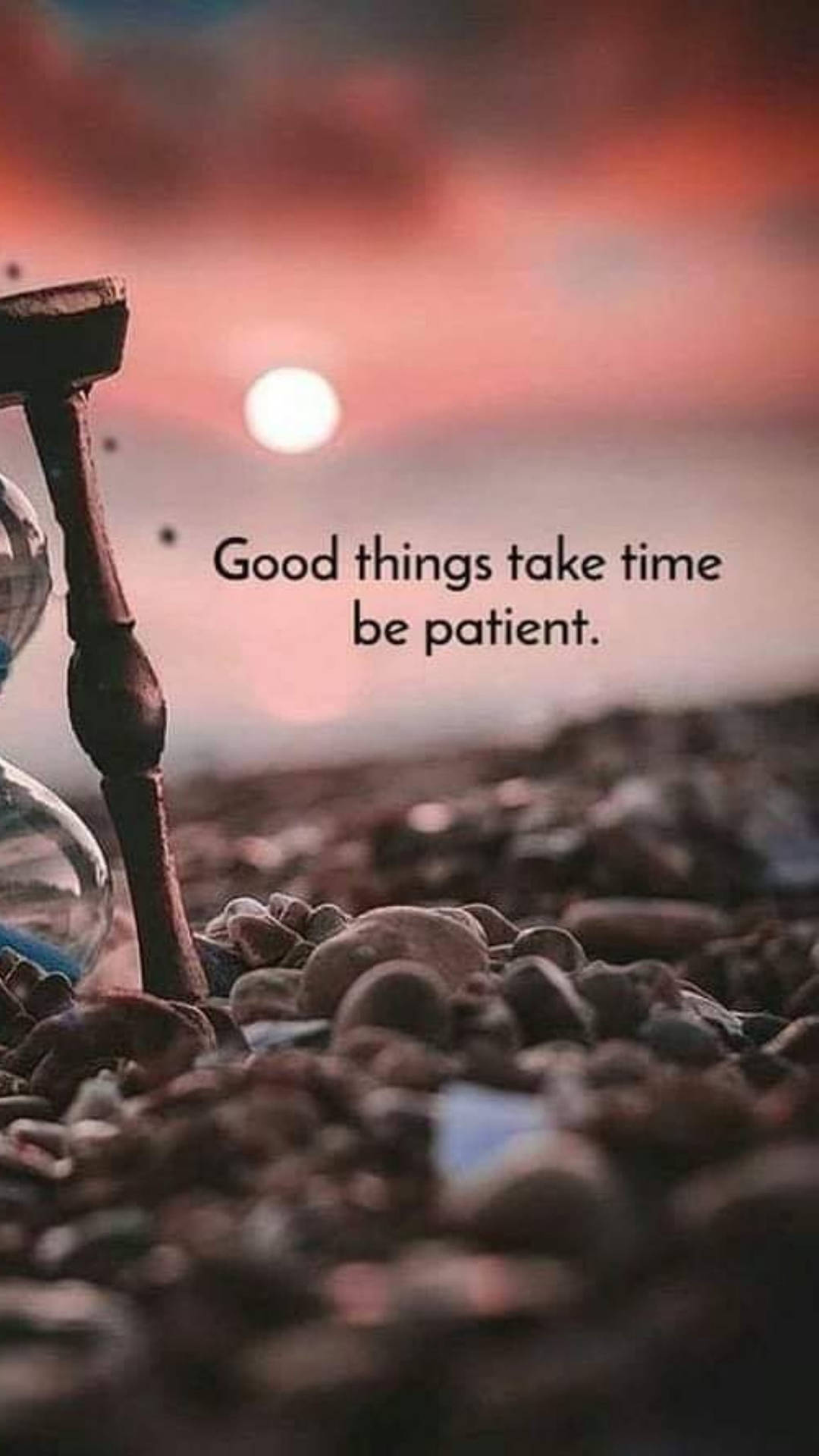 日落時卵石上的木製沙漏，文字 good things take time be patient — 聖誕美學 GIF 壁紙