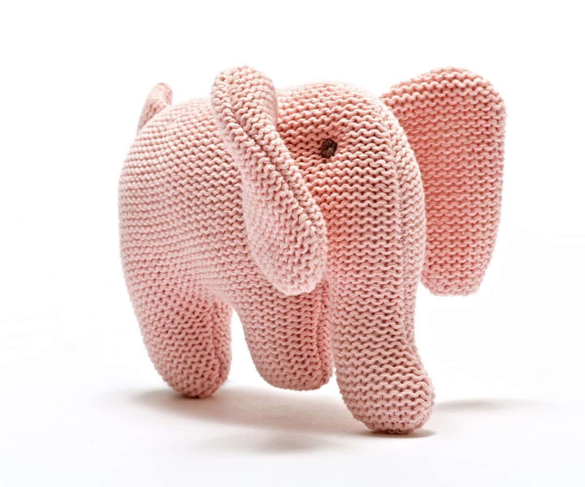 Pink Elephant 桌布 壁紙 — 一個柔軟的粉紅色編織大象玩具，站在乾淨的白色背景前，帶有可見的針織紋理和一個小的棕色鈕扣眼睛。