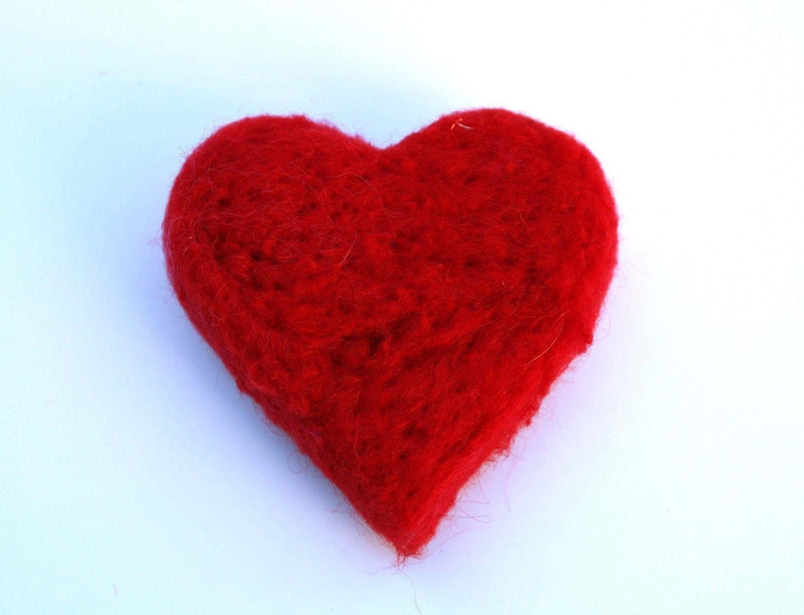 Red Heart 桌布 壁紙 — 一個柔軟的紅色絨布心形，帶有紋理纖維，放置在潔淨的白色背景上。