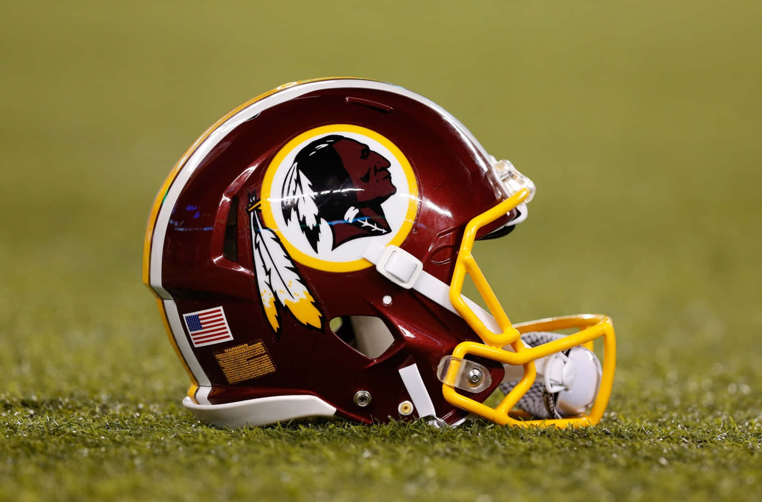 Washington Football 桌布 壁紙 — 一個栗色嘅華盛頓美式足球隊頭盔，配有黃色面罩，放在鮮綠色嘅草地上。