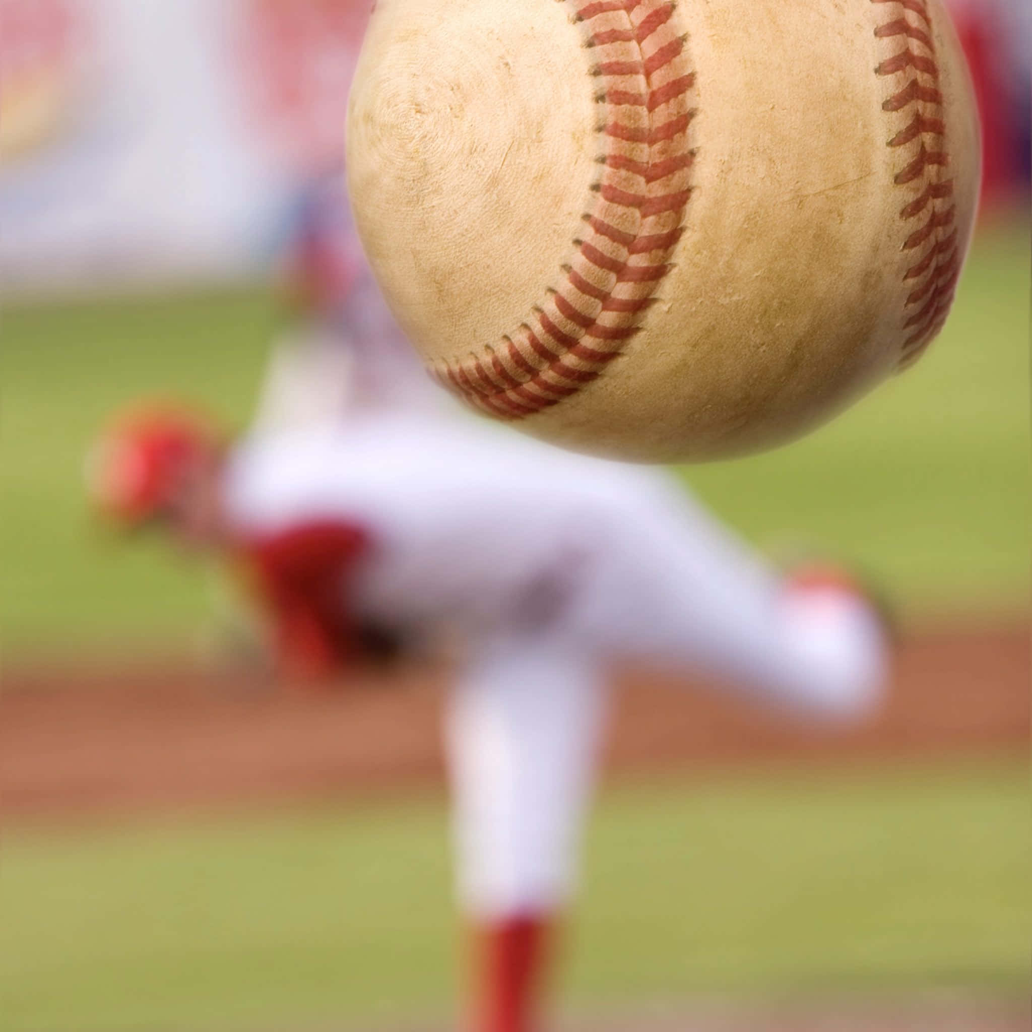Cool Baseball 桌布 壁紙 — 一個棒球在空中嘅特寫，背景係模糊嘅投手喺綠色球場上。
