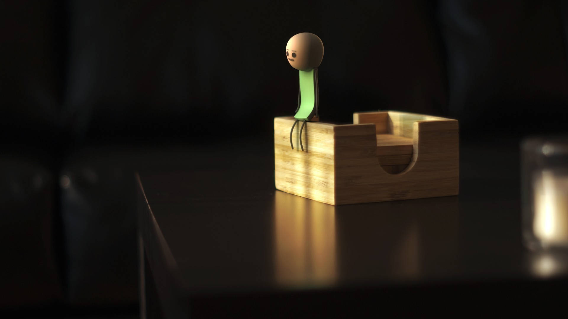Cyanide and Happiness 3D Greenshirt 壁紙 — 一個極簡的3D渲染火柴人，綠色軀幹，坐在暗色桌子上的木箱上，處於溫暖的環境光中。