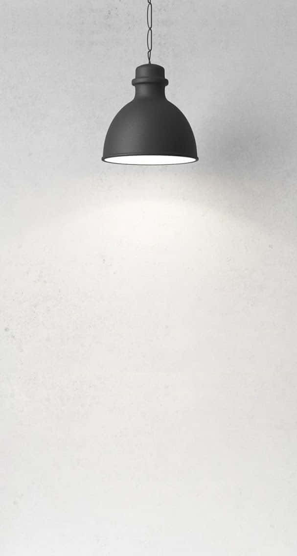 Minimalist Photography 桌布 壁紙 — 一個極簡風格的黑色吊燈懸掛在有紋理的米白色牆壁上，下方散發出柔和的光芒。