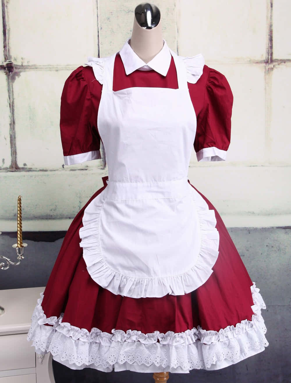 Lolita Fashion 桌布 壁紙 — 一個模特兒展示一件復古風格的紅白女傭服，帶有荷葉邊細節，背景是風化的牆壁。