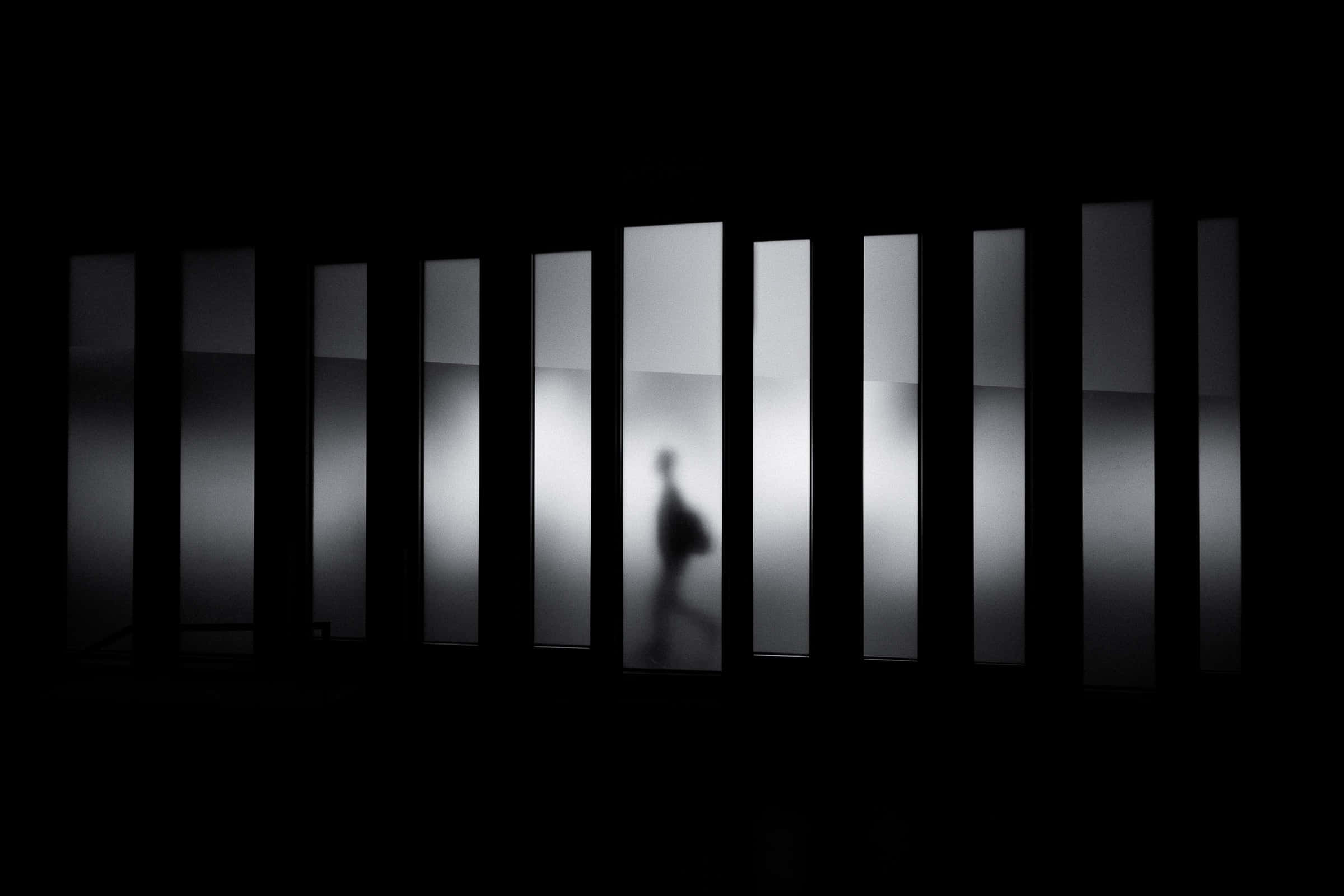 shadow 桌布 壁紙 — 一個模糊的人影穿過黑暗走廊中一排垂直的磨砂玻璃板。