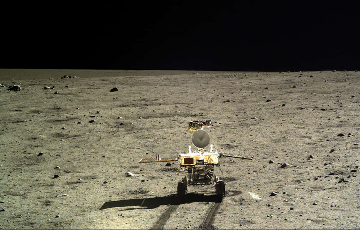 Lunar Rover 桌布 壁紙 — 一個機械人探測車站在荒蕪的灰色月球表面，在黑色天空下投下長長的影子。