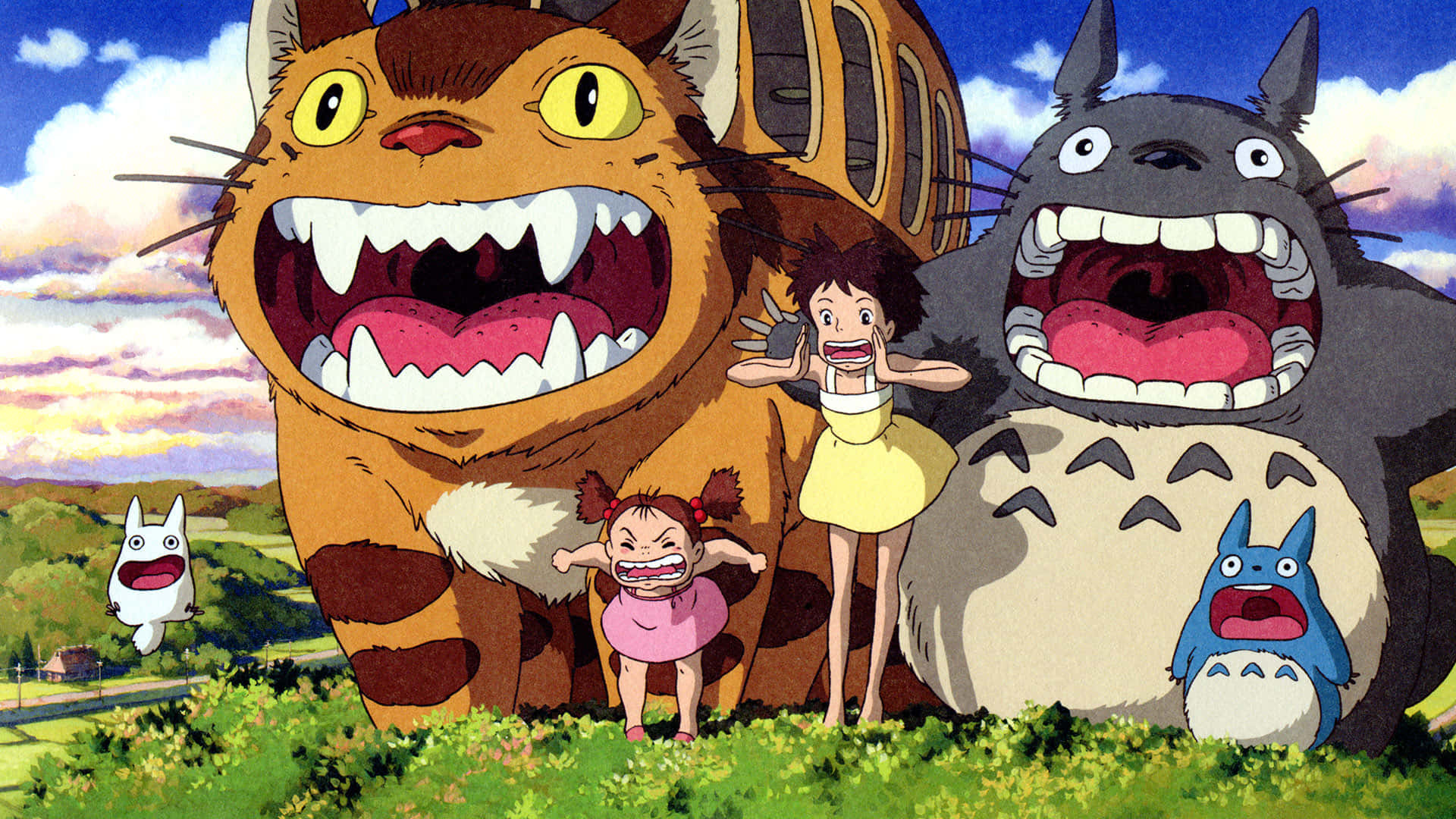 my neighbor totoro 桌布 壁紙 — 一個歡樂的場景，有巨大的貓狀生物和孩子們在色彩繽紛的天空下，在充滿活力的綠色田野中大笑。