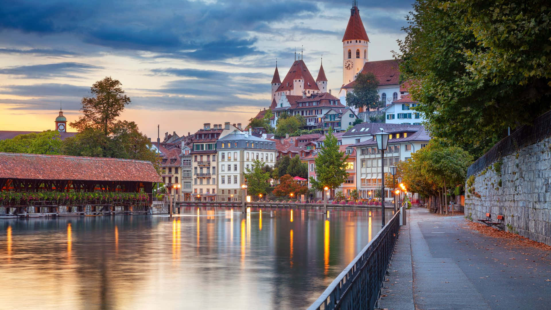Switzerland 桌布 壁紙 — 一個歷史悠久的歐洲河畔小鎮，城堡塔樓和有蓋橋樑倒映在平靜的水面上，呈現寧靜的黃昏景色。