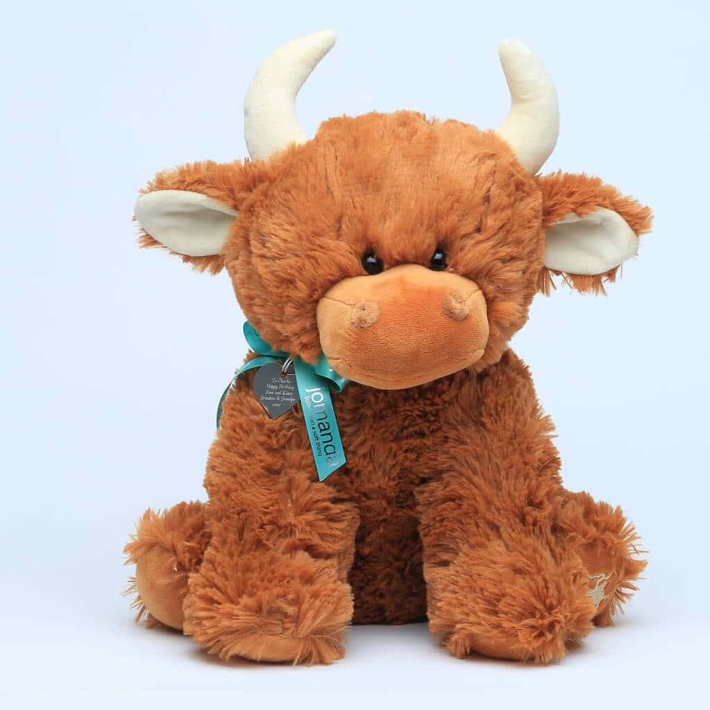 Cuddly 桌布 壁紙 — 一個毛茸茸的棕色高地牛毛絨玩具，有白色角和耳朵，坐在柔和的藍色背景前。