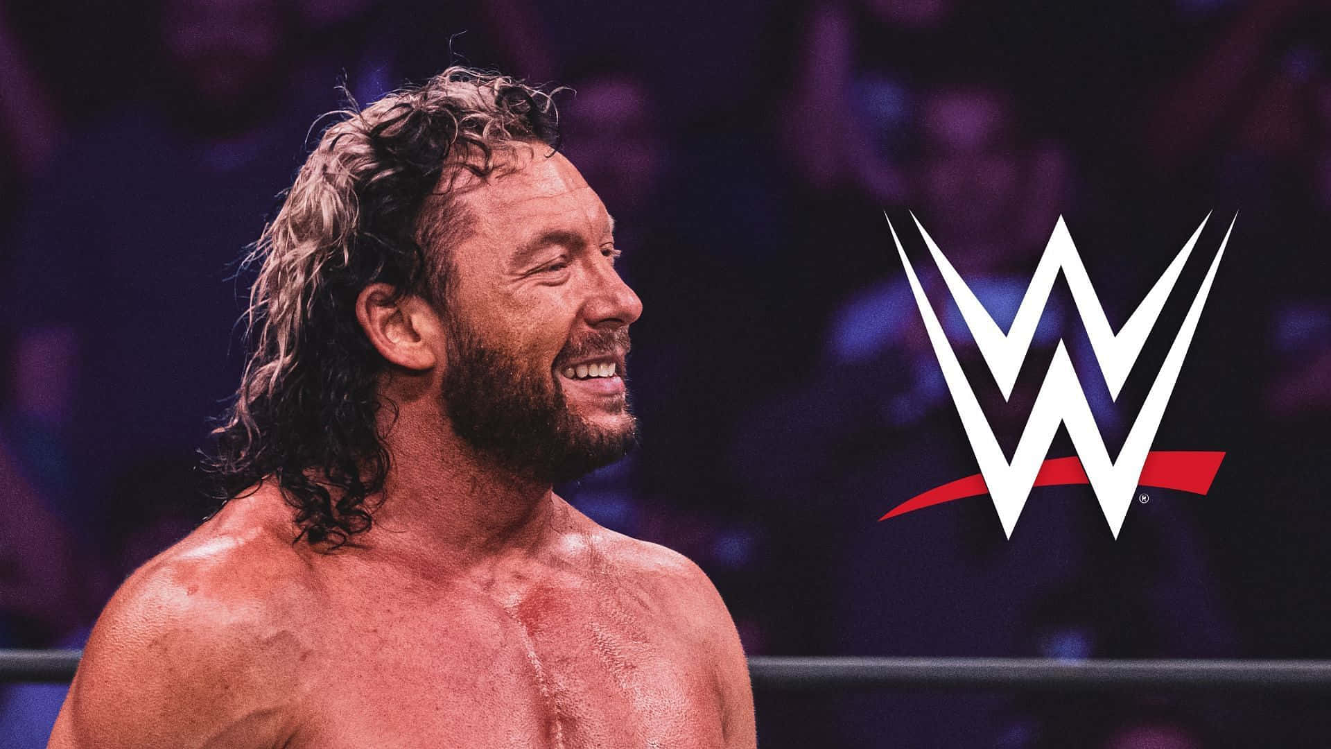 Kenny Omega Beside The WWE Logo 壁紙 — 一個汗流浹背的鬍鬚摔角手在擂台上得意地咧嘴笑，WWE標誌在他身後發光。