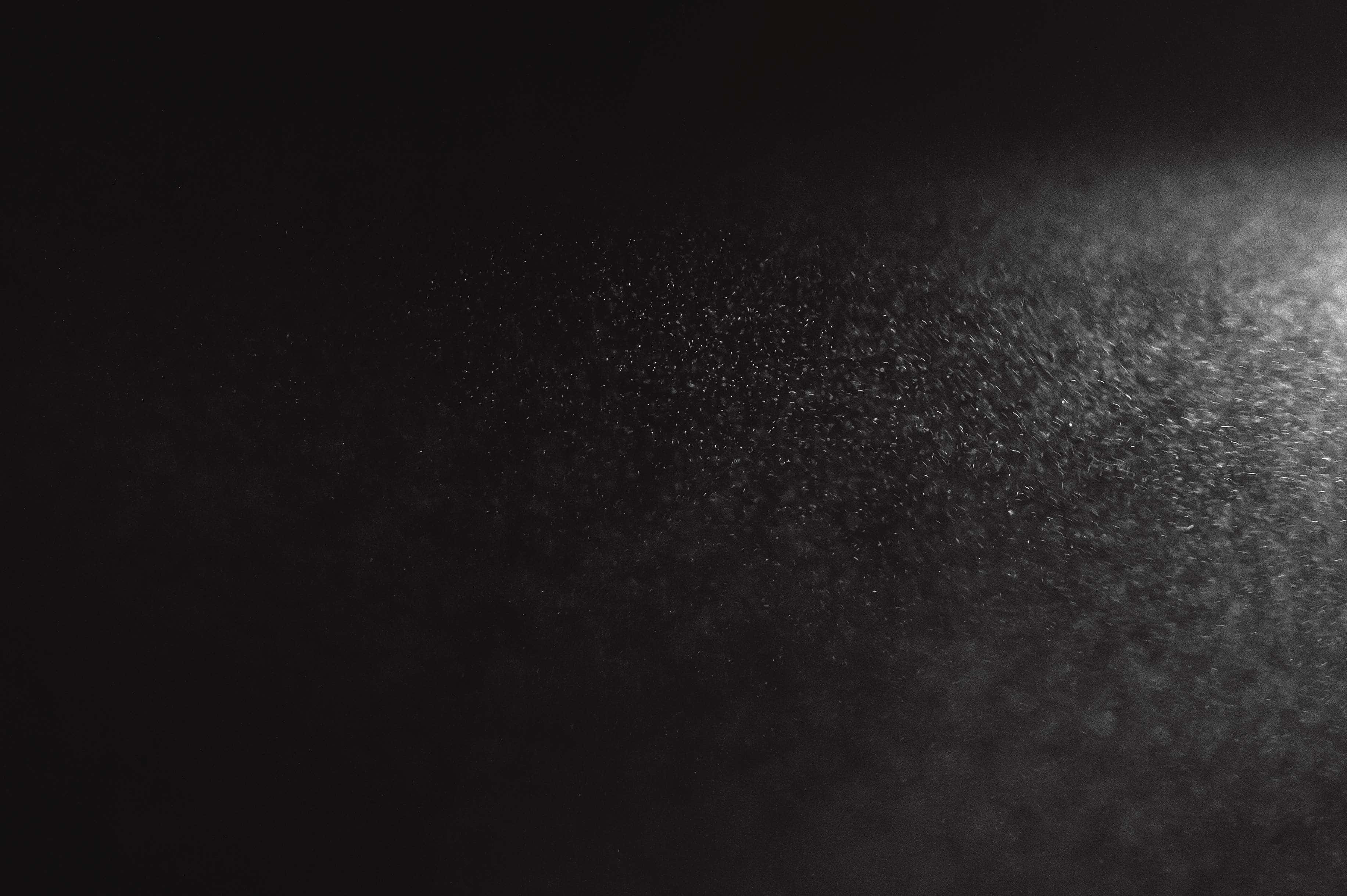 Dust 桌布 壁紙 — 一個深色紋理表面，帶有柔和的光線漸變，在極簡抽象構圖中顯現出細微顆粒。