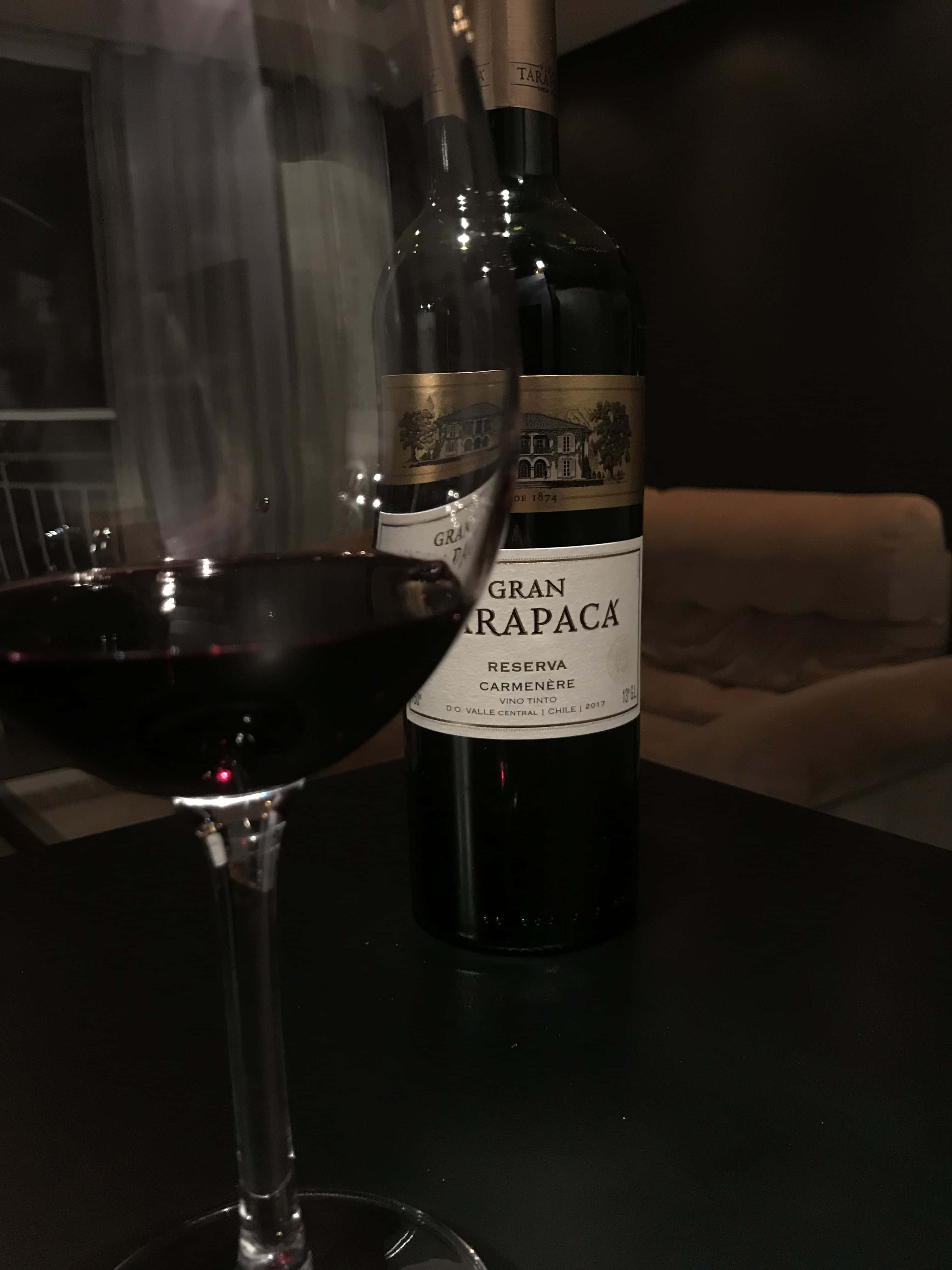 Black Wine 桌布 壁紙 — 一個深色酒瓶和酒杯放在一張桌子上，房間光線昏暗，背景有一張沙發。