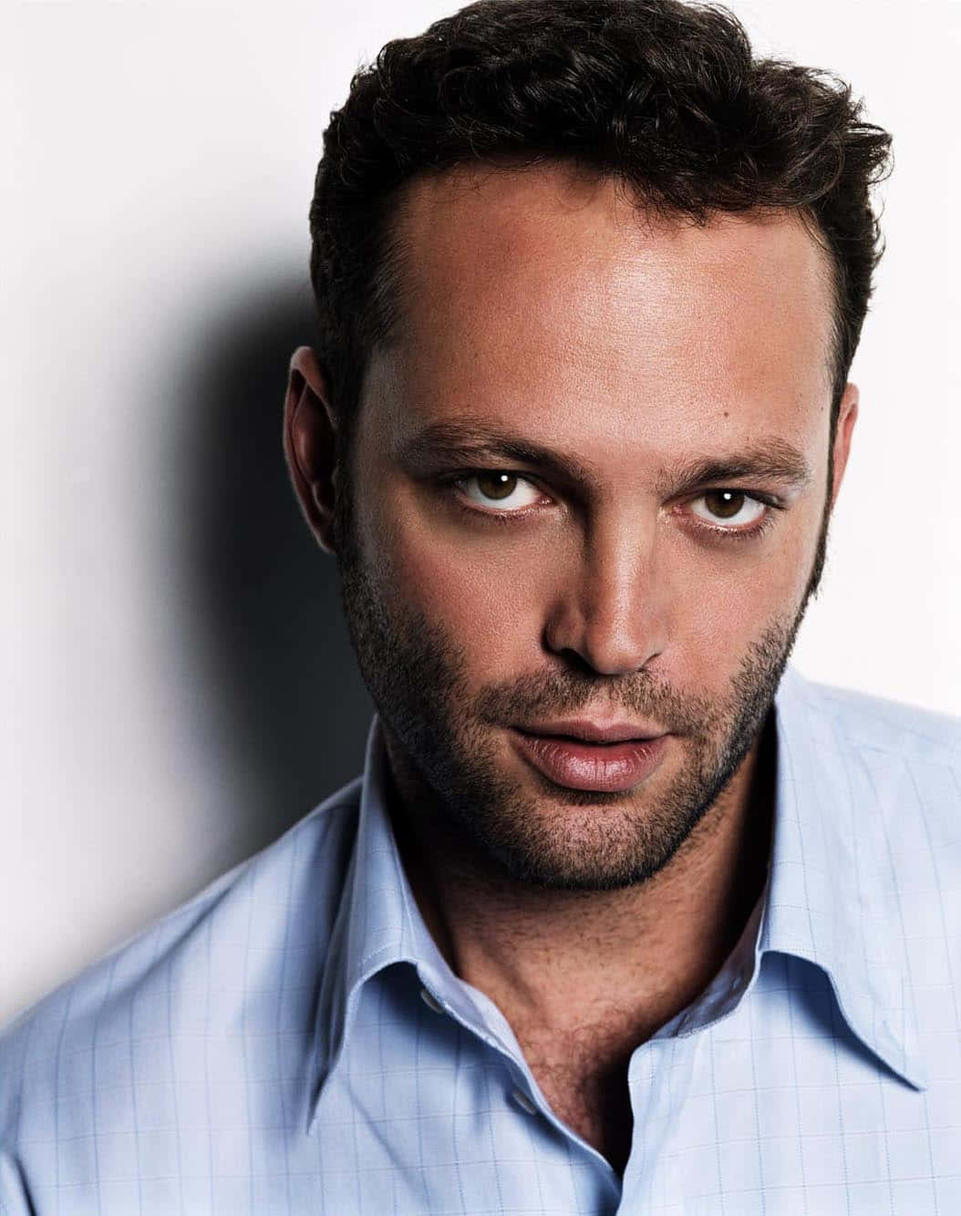 Vince Vaughn 桌布 壁紙 — 一個深色頭髮、鬚根的男人嘅特寫肖像，著住淺藍色格仔恤衫，背景係純白色。