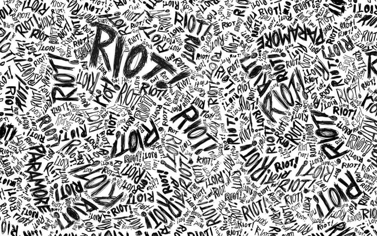 Black And White Typography 桌布 壁紙 — 一個混亂的黑白牆紙，充滿了像 'RIOT' 和 'PARA MORE' 這樣旋轉的手寫字，採用大膽的塗鴉風格。