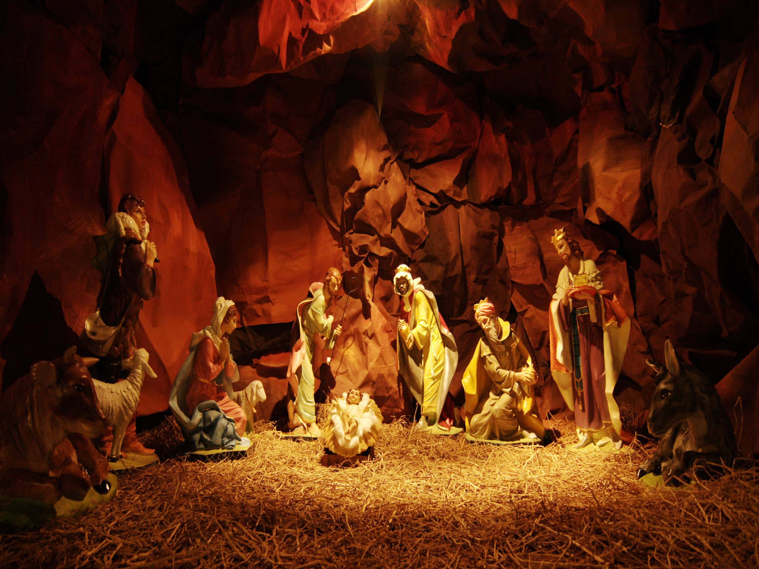 Nativity 桌布 壁紙 — 一個溫暖照明的馬槽場景，有瑪利亞、約瑟、嬰兒耶穌、牧羊人、智者及動物聚集在岩石洞穴中。
