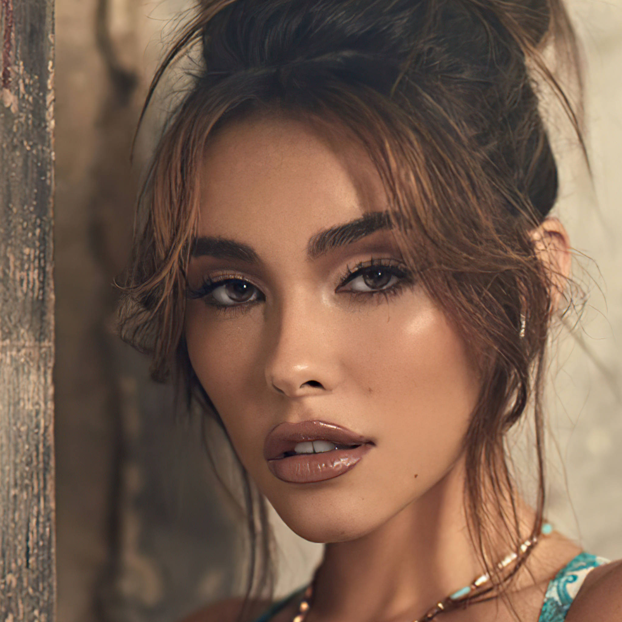 Madison Beer Vanity Fair 壁紙 — 一個特寫肖像，一位深色頭髮、妝容大膽的女性，在質樸的木質背景下直視鏡頭。