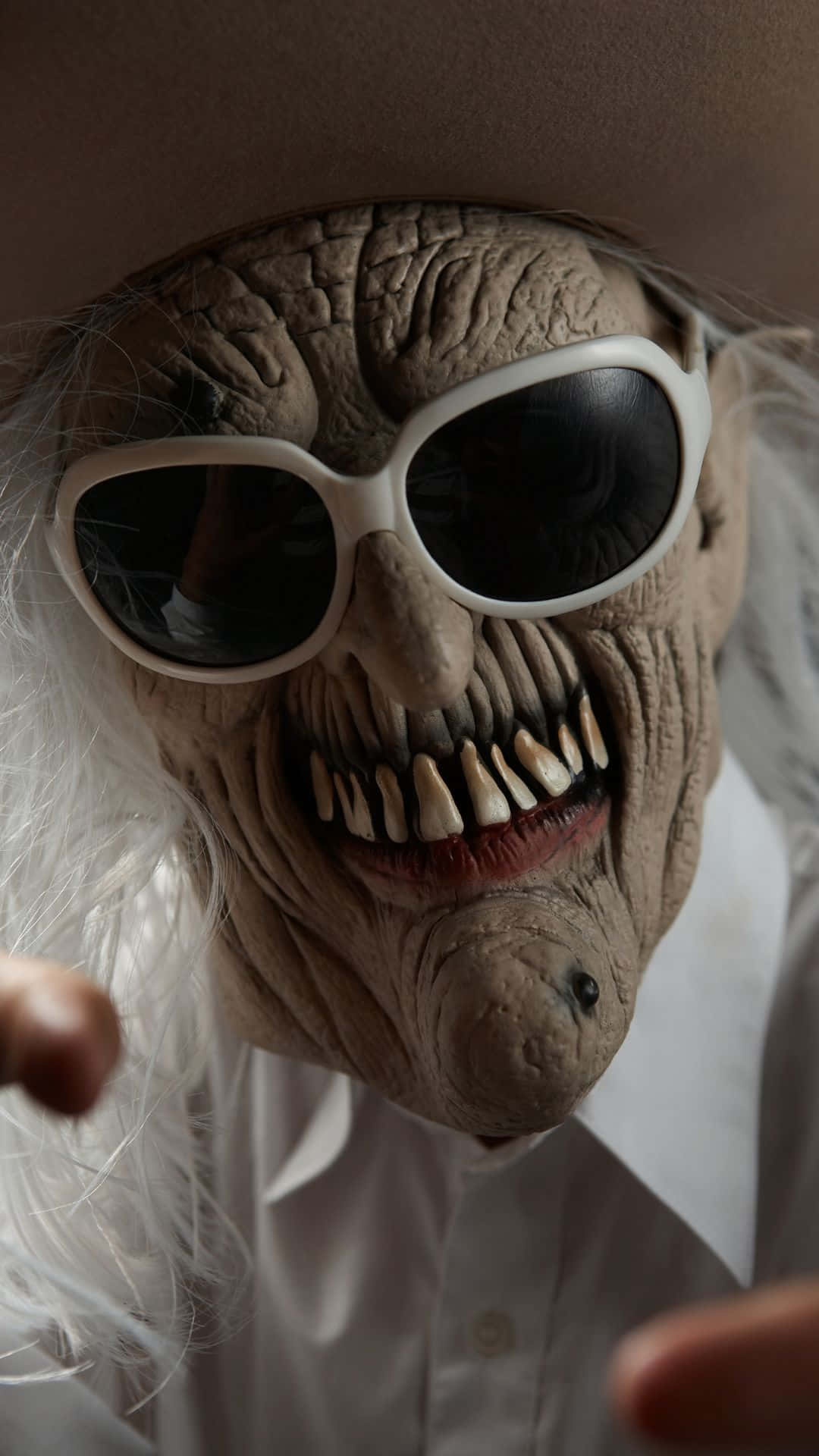 Horror Masks 桌布 壁紙 — 一個特寫鏡頭，展示一個戴著白色太陽眼鏡、咧嘴露出牙齒、頭戴棕色帽子的怪異皺紋面具。