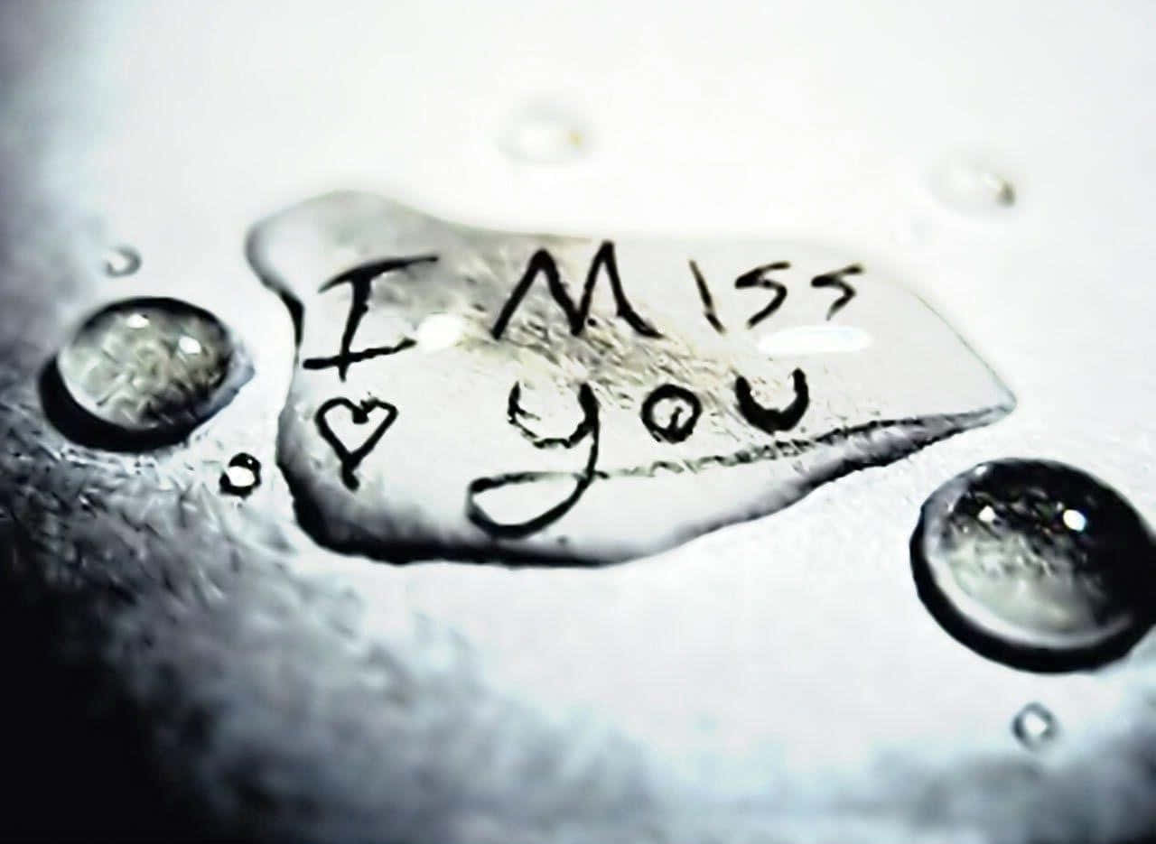 Sad Love 桌布 壁紙 — 一個特寫鏡頭，水滴在帶有紋理的白色表面上顯現出親手寫的「I Miss You」和一個心形。