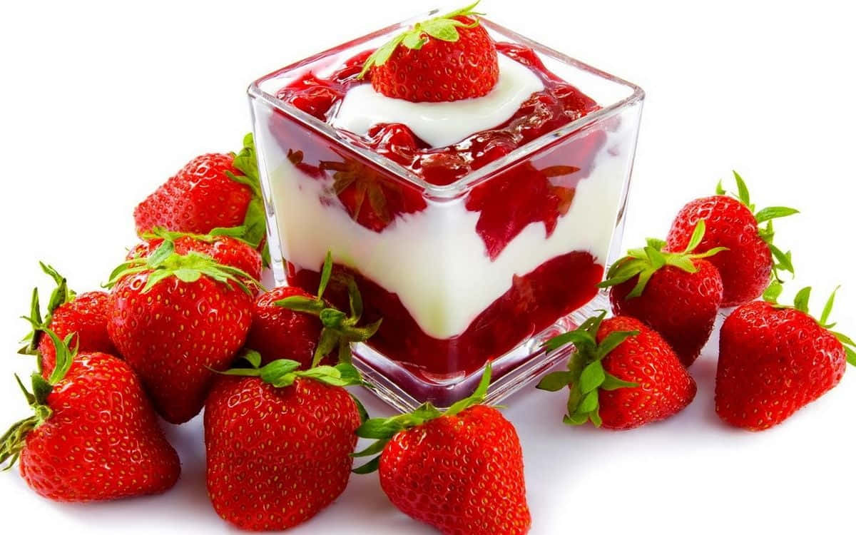 Red Strawberry 桌布 壁紙 — 一個玻璃立方體裝滿了奶油乳酪和鮮紅的草莓醬，上面放著新鮮草莓，周圍是整個草莓，背景為白色。