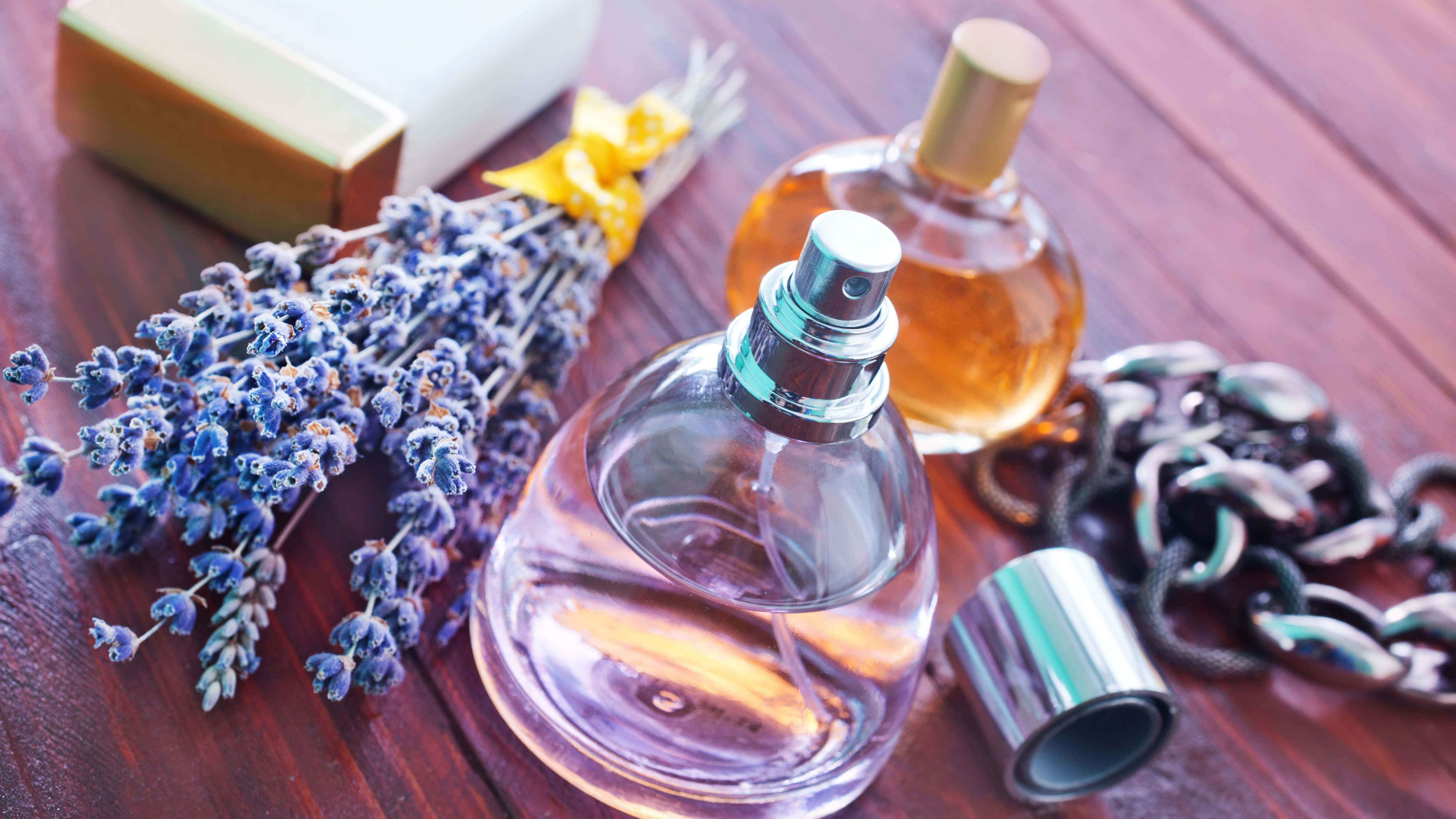 Fragrance 桌布 壁紙 — 一個玻璃香水瓶，帶有薰衣草枝條和一條鏈條，放在一個豐富的木質表面上，旁邊有一塊肥皂。