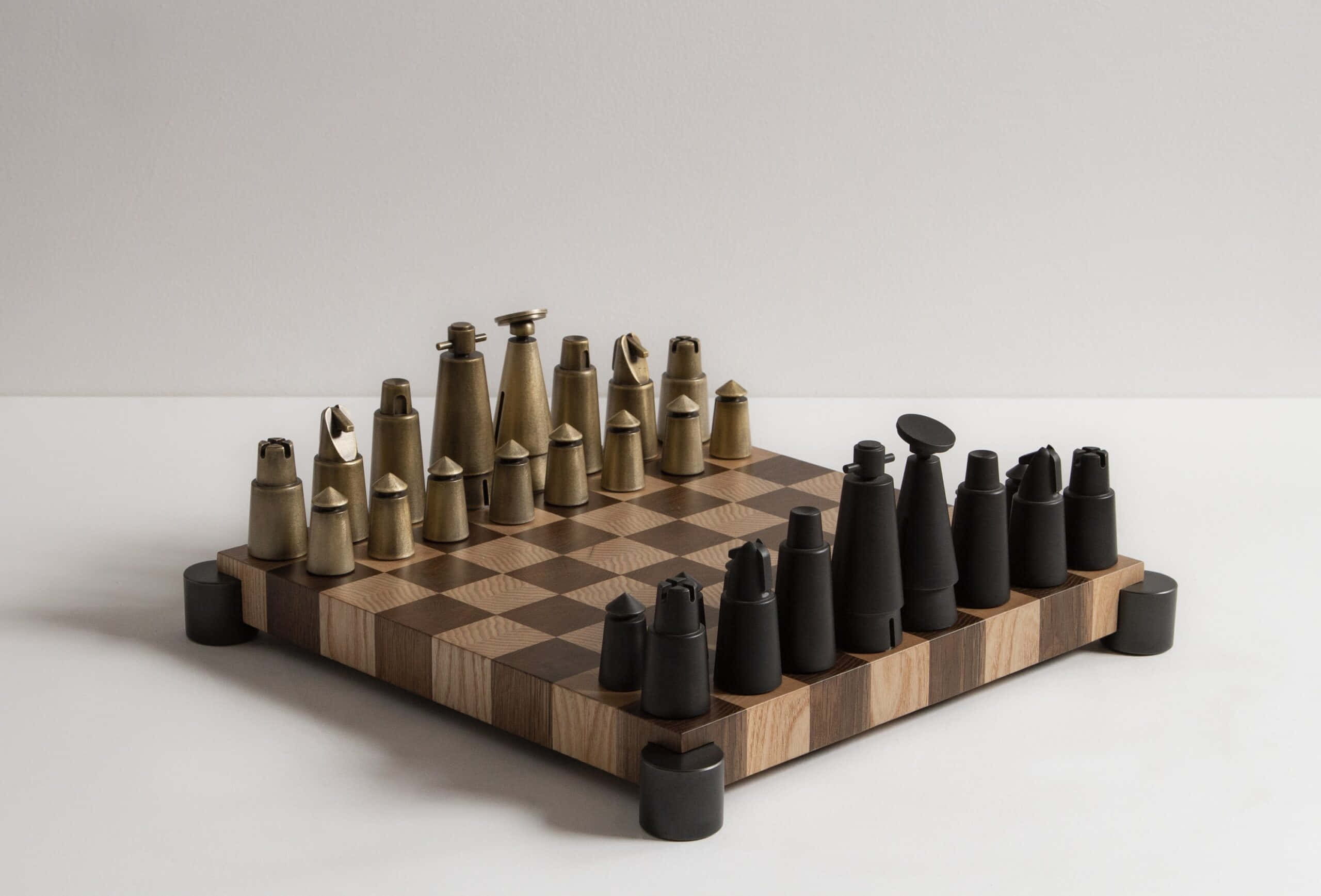 Chessboard 桌布 壁紙 — 一個現代國際象棋套裝，帶有金屬和磨砂黑色棋子，放在木製棋盤上，背景為簡約白色。