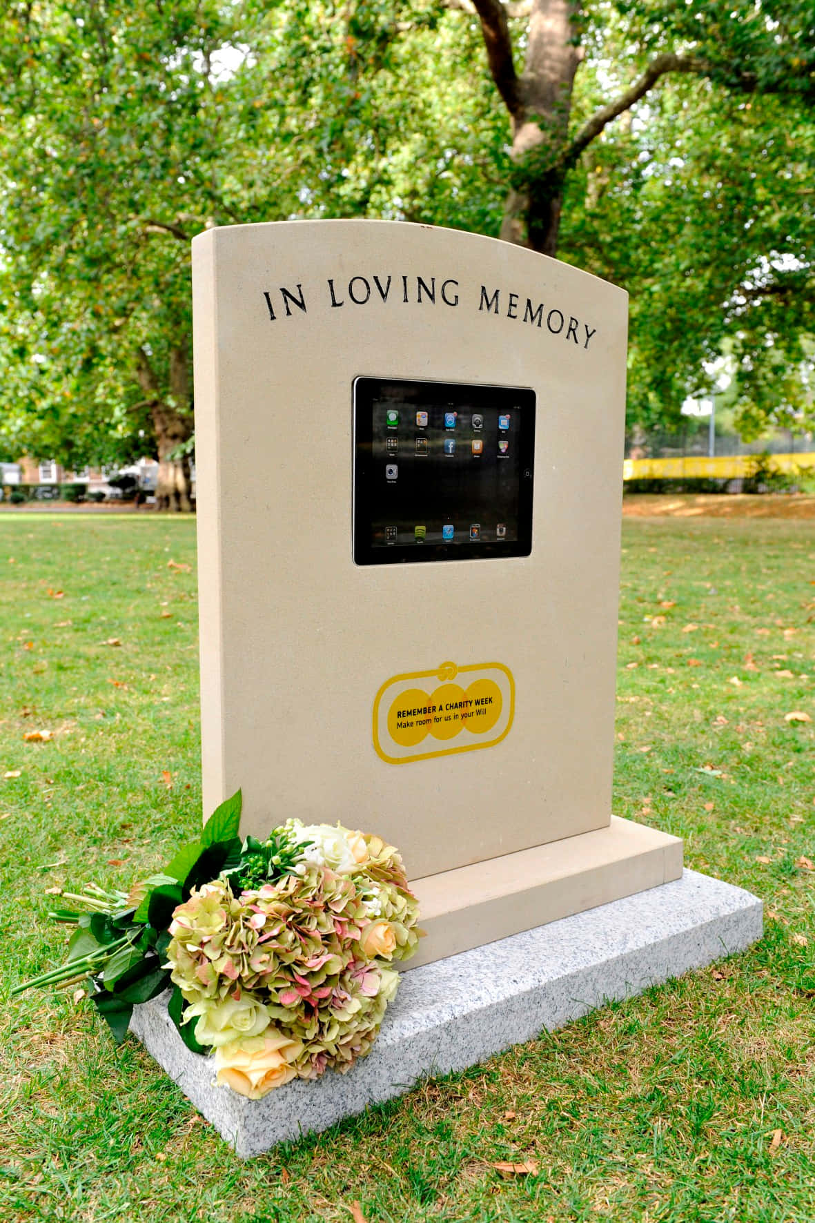Gravestone 桌布 壁紙 — 一個現代紀念石位於草地公園，內嵌一塊平板，底部有新鮮繡球花。