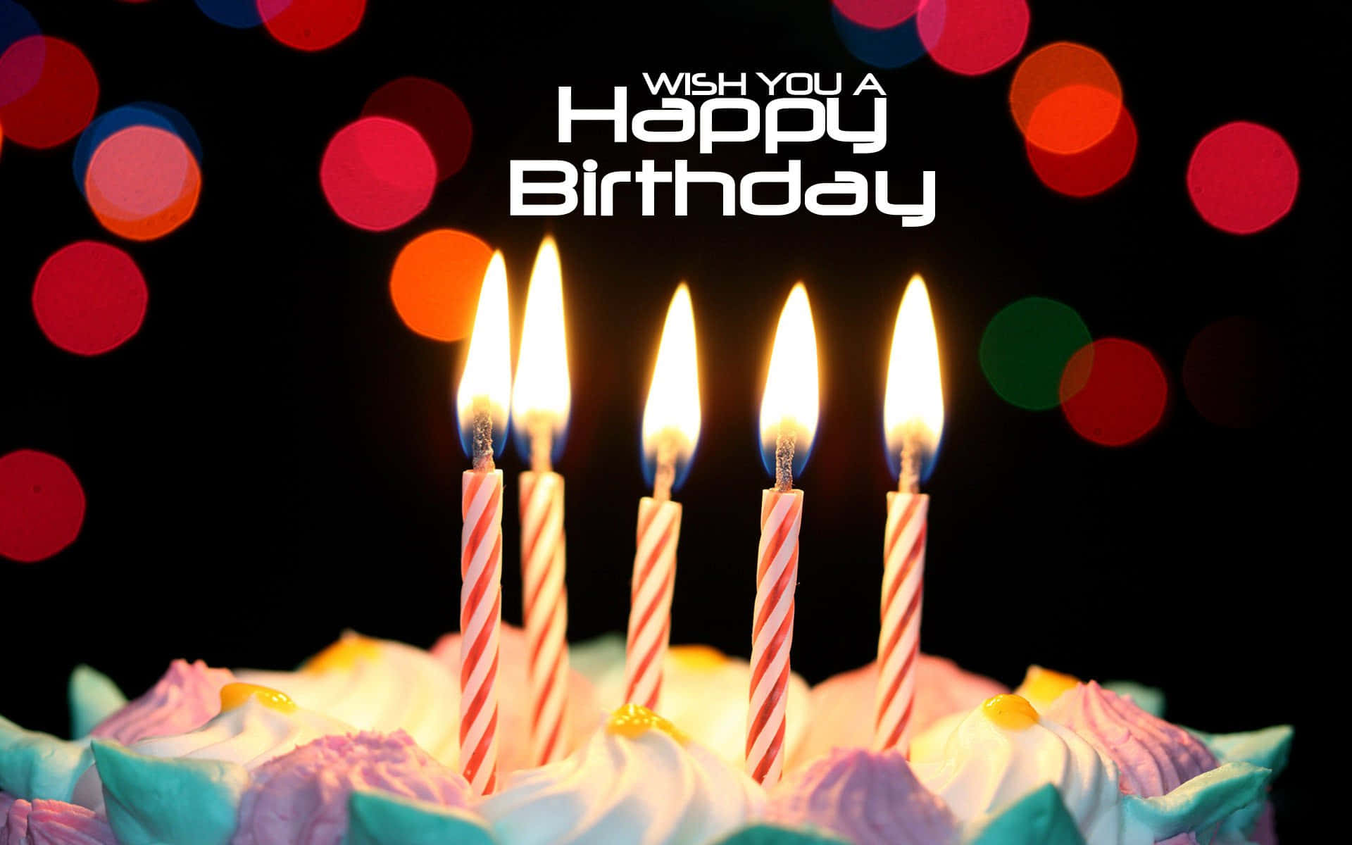 Birthday Wishes 桌布 壁紙 — 一個生日蛋糕，上面有五根點燃的蠟燭和彩色糖霜，背景是深色帶有節日氣氛的散景燈光。