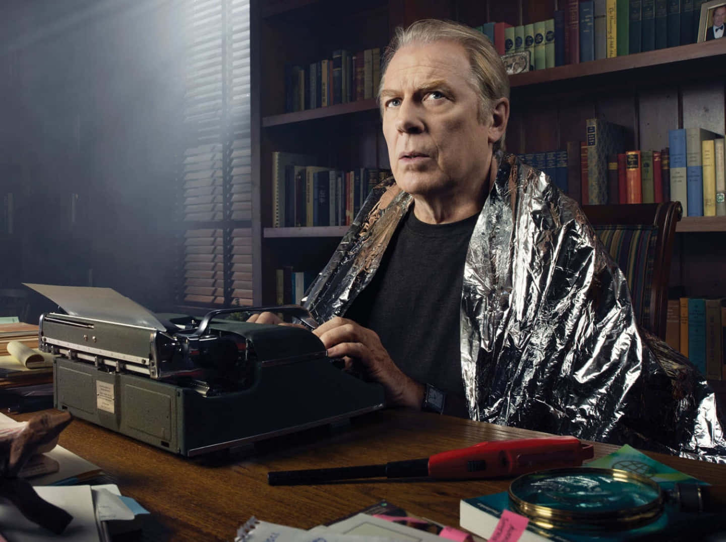 Michael Mckean 桌布 壁紙 — 一個用錫紙包裹的男人坐在一張雜亂的書桌前，桌上放著一部復古打字機，房間光線昏暗，到處都是書。