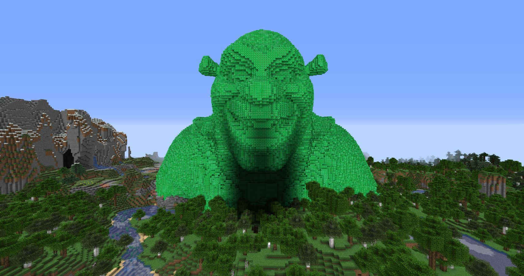 Minecraft Emeralds 桌布 壁紙 — 一個由Minecraft方塊製成的巨大綠色史力加，在一片有河流和山脈的森林景觀上空聳立，天空清澈湛藍。