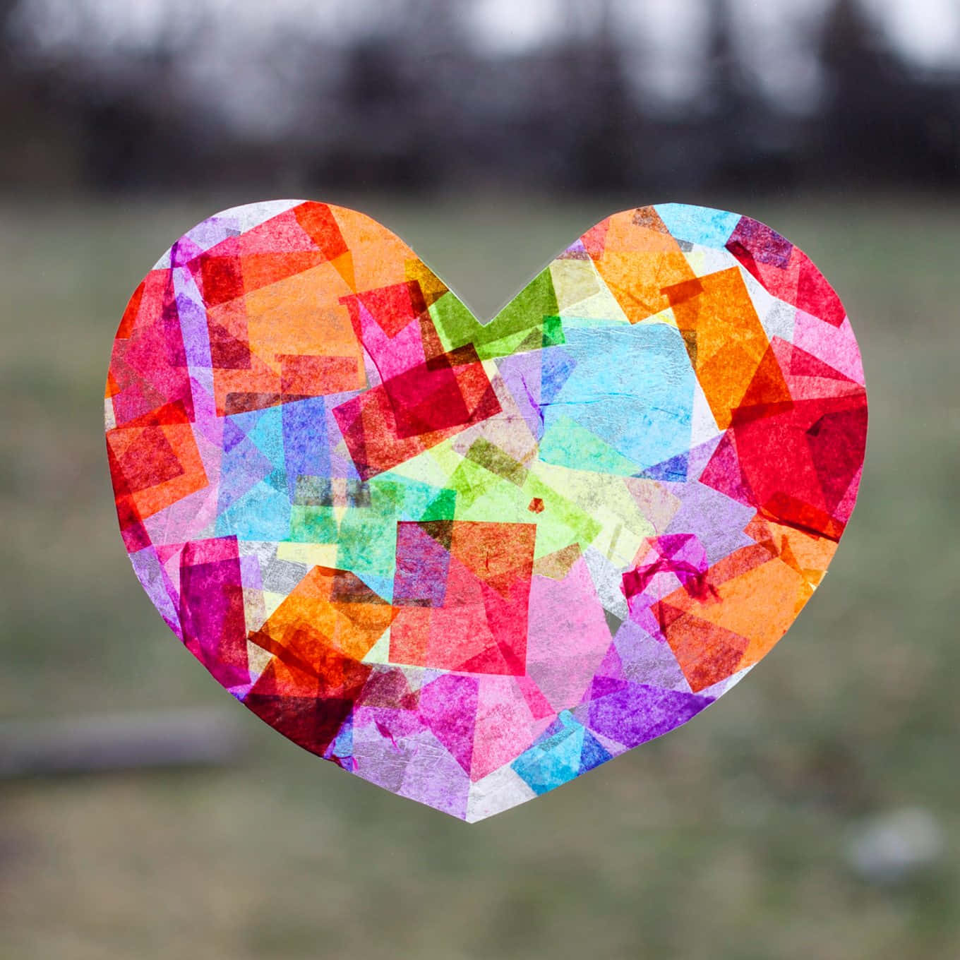 Heart Art 桌布 壁紙 — 一個由彩色半透明正方形製成的鮮豔心形彩色玻璃窗，懸掛在模糊的戶外背景前。
