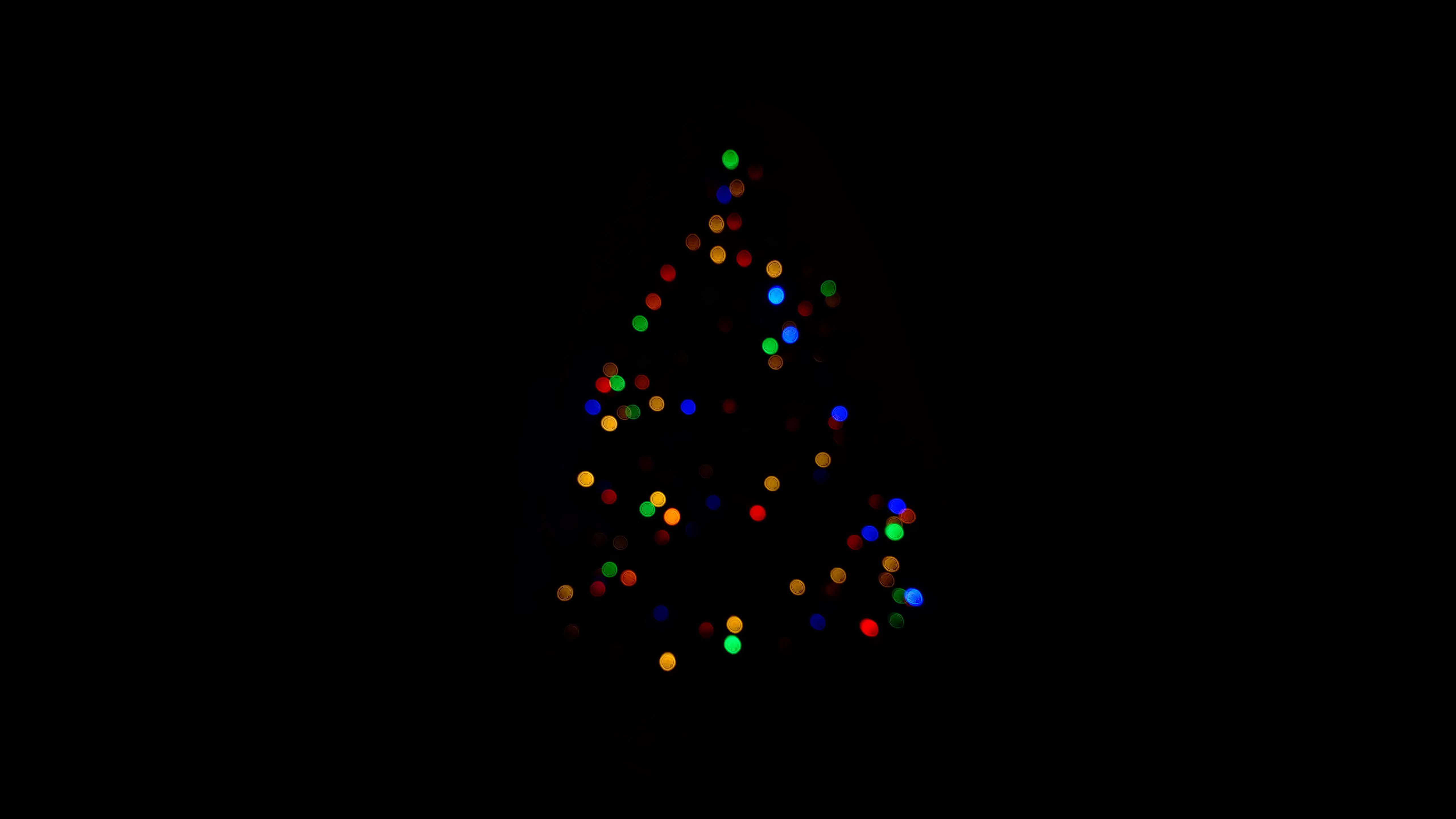Dark Christmas 桌布 壁紙 — 一個由彩色發光燈光組成的散景聖誕樹，背景為黑色。