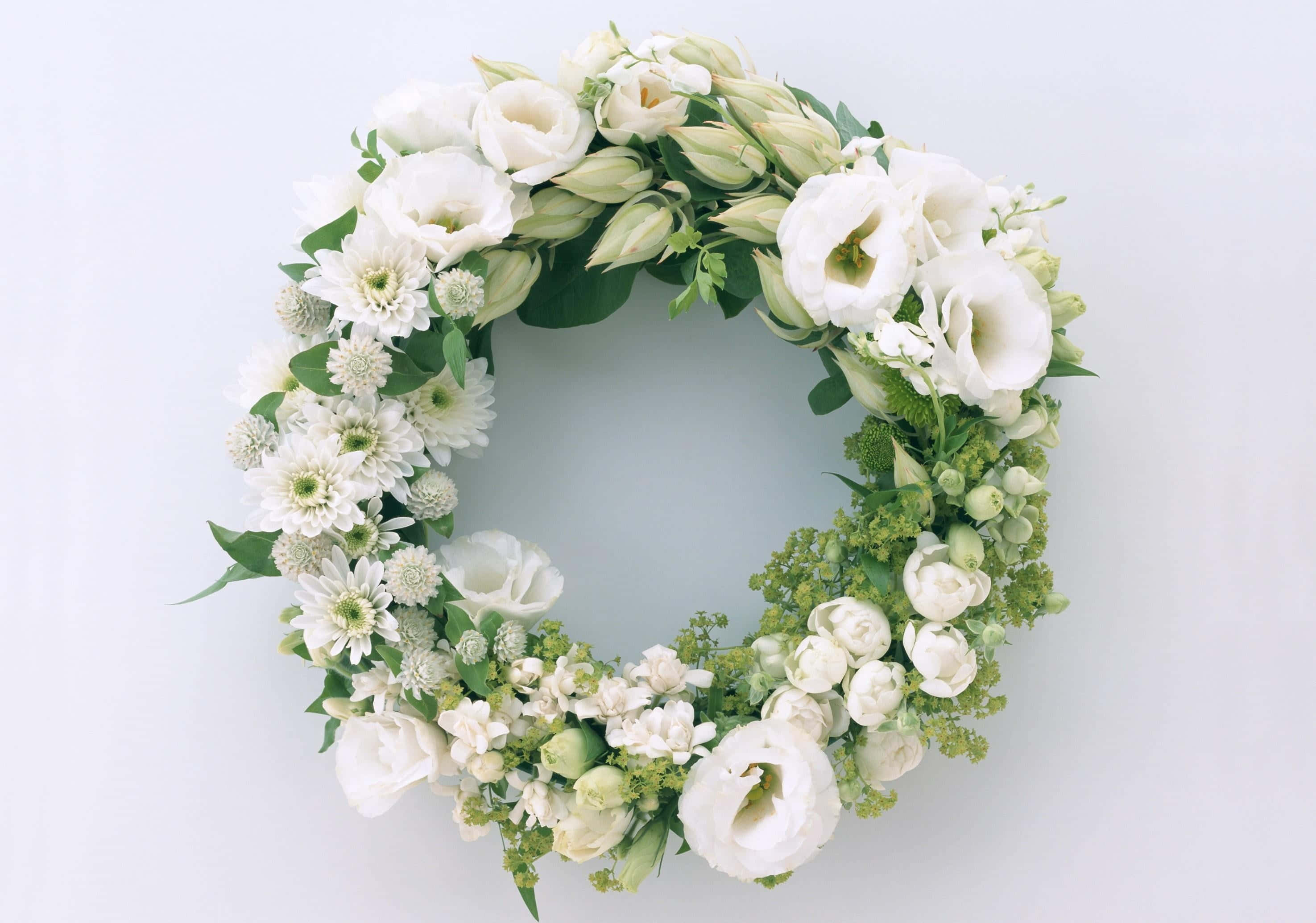 Floral Wreath 桌布 壁紙 — 一個由白色花朵和綠色植物組成的圓形花環，靠在柔和的淺灰色背景上。