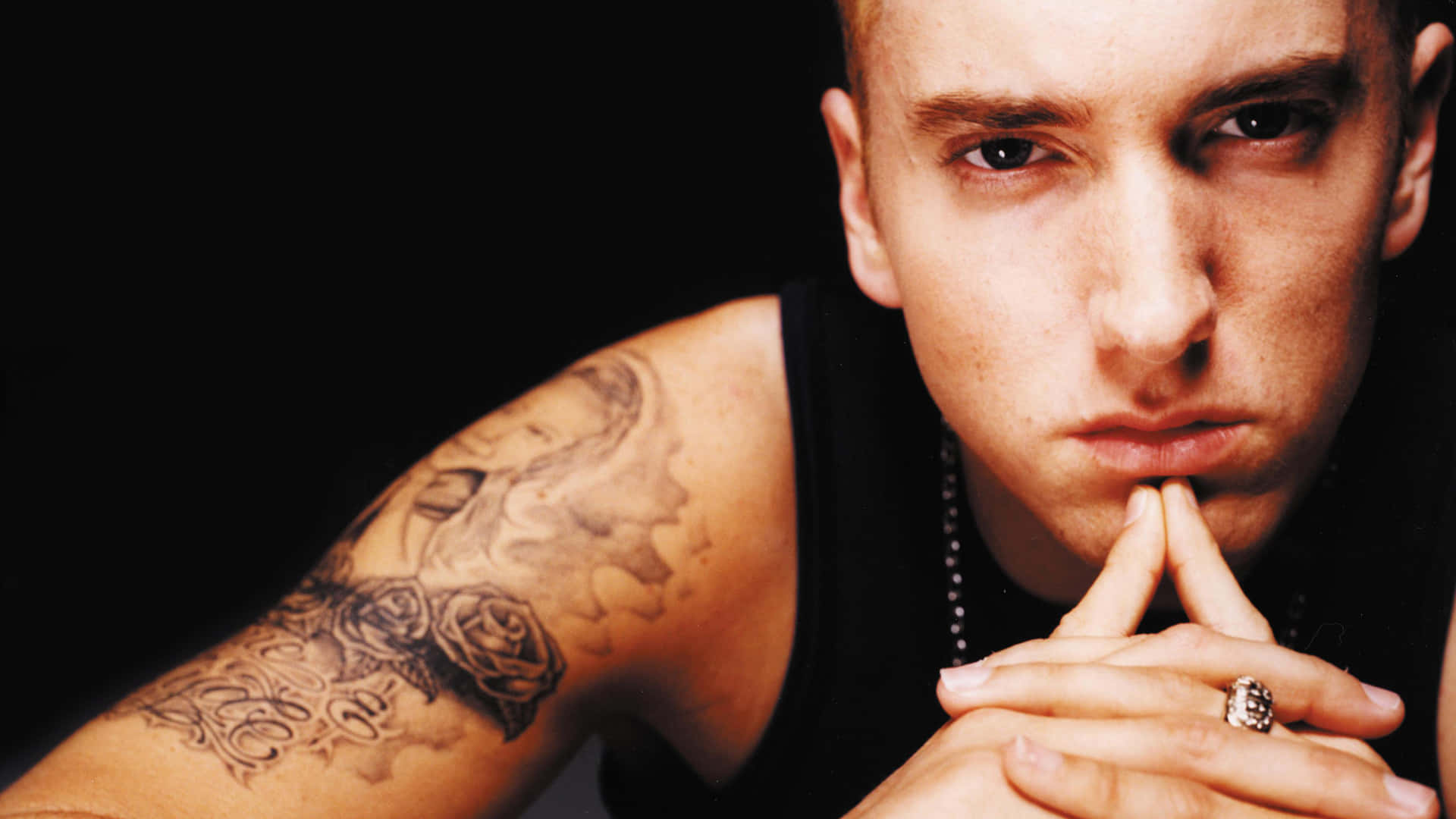 Eminem 桌布 壁紙 — 一個男人嘅近距離肖像，佢有紋身手臂同嚴肅表情，背景係黑色。