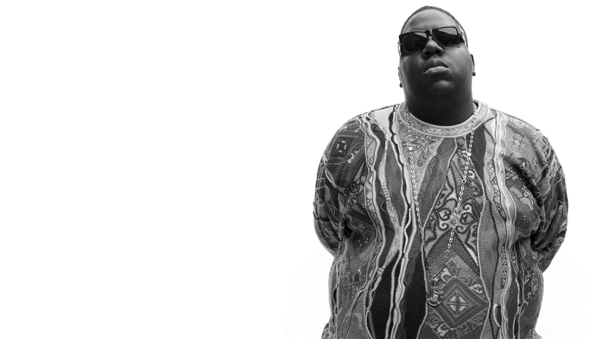 Notorious B.I.G. Biggie Smalls 壁紙 — 一個男人戴著太陽眼鏡和圖案襯衫，在純白色背景前的黑白肖像。