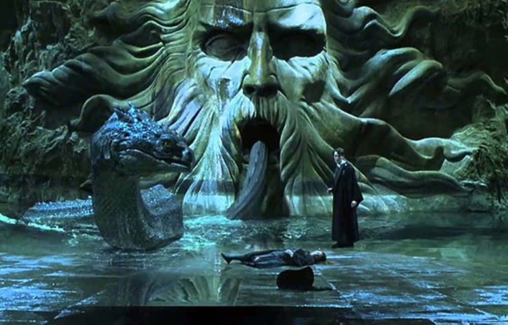 Harry Potter Serpent 桌布 壁紙 — 一個男人站在一個從水中浮現的巨大石臉前，旁邊有一條蛇形生物，身處神秘洞穴中。