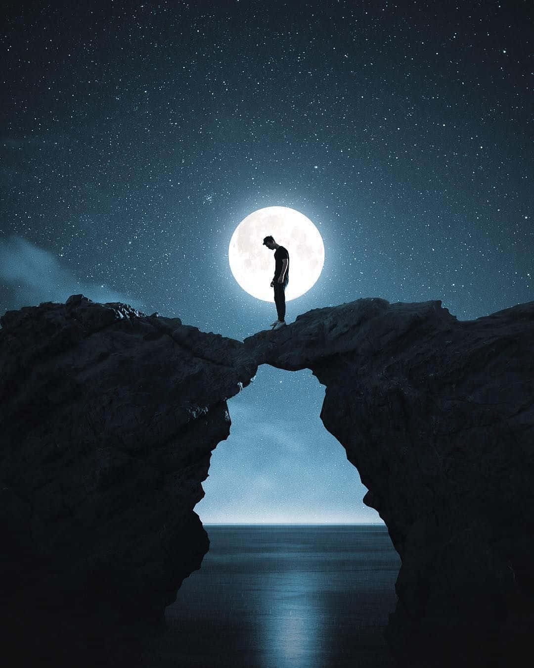一個男人站在夜空中的岩石上 壁紙