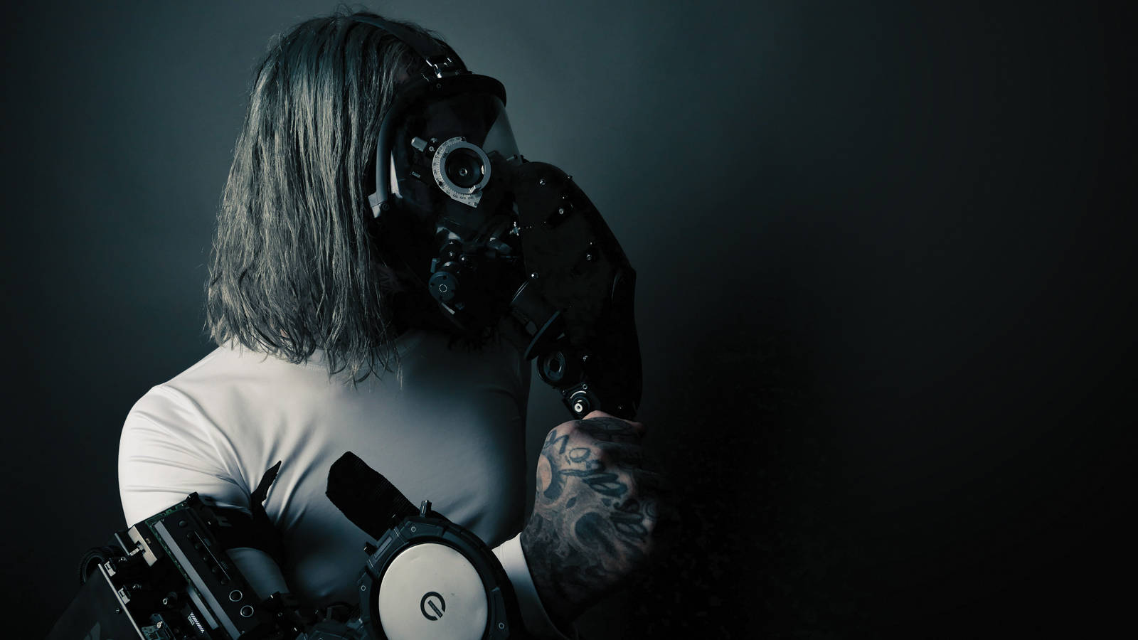 Ghostemane 桌布 壁紙 — 一個留著及肩長髮的人，在黑暗的攝影棚背景下戴著防毒面具和機械手臂。