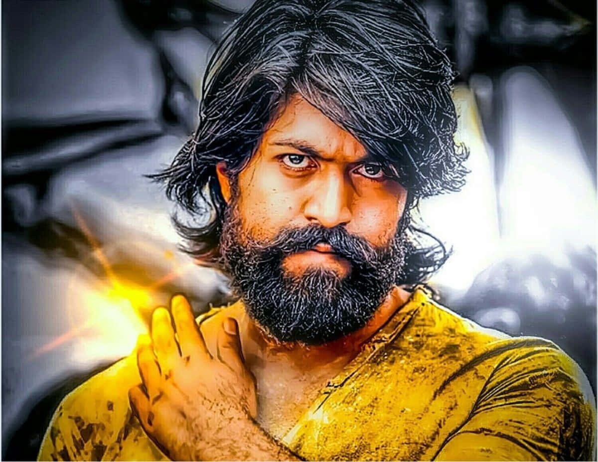 Kgf 2 桌布 壁紙 — 一個留著深色鬍鬚、眼神銳利的男人穿著黃色襯衫，身後有發光的光芒爆發。