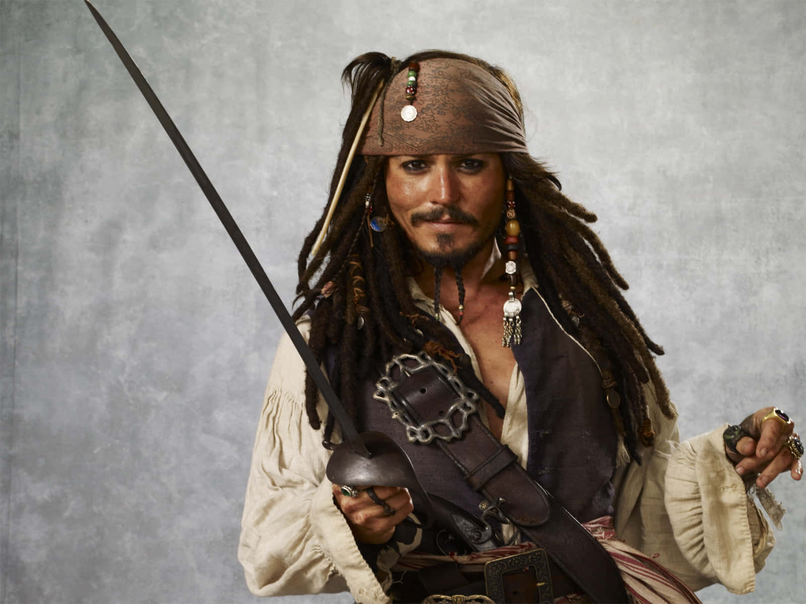 Pirates Of The Caribbean 桌布 壁紙 — 一個留著辮子、戴著頭巾的海盜，在紋理灰色背景前揮舞著劍。
