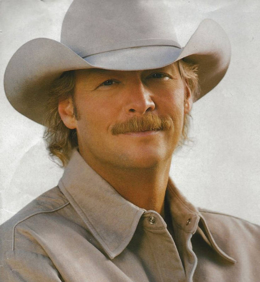 Alan Jackson 桌布 壁紙 — 一個留鬍子、戴牛仔帽的男人在純色背景下溫暖地微笑。