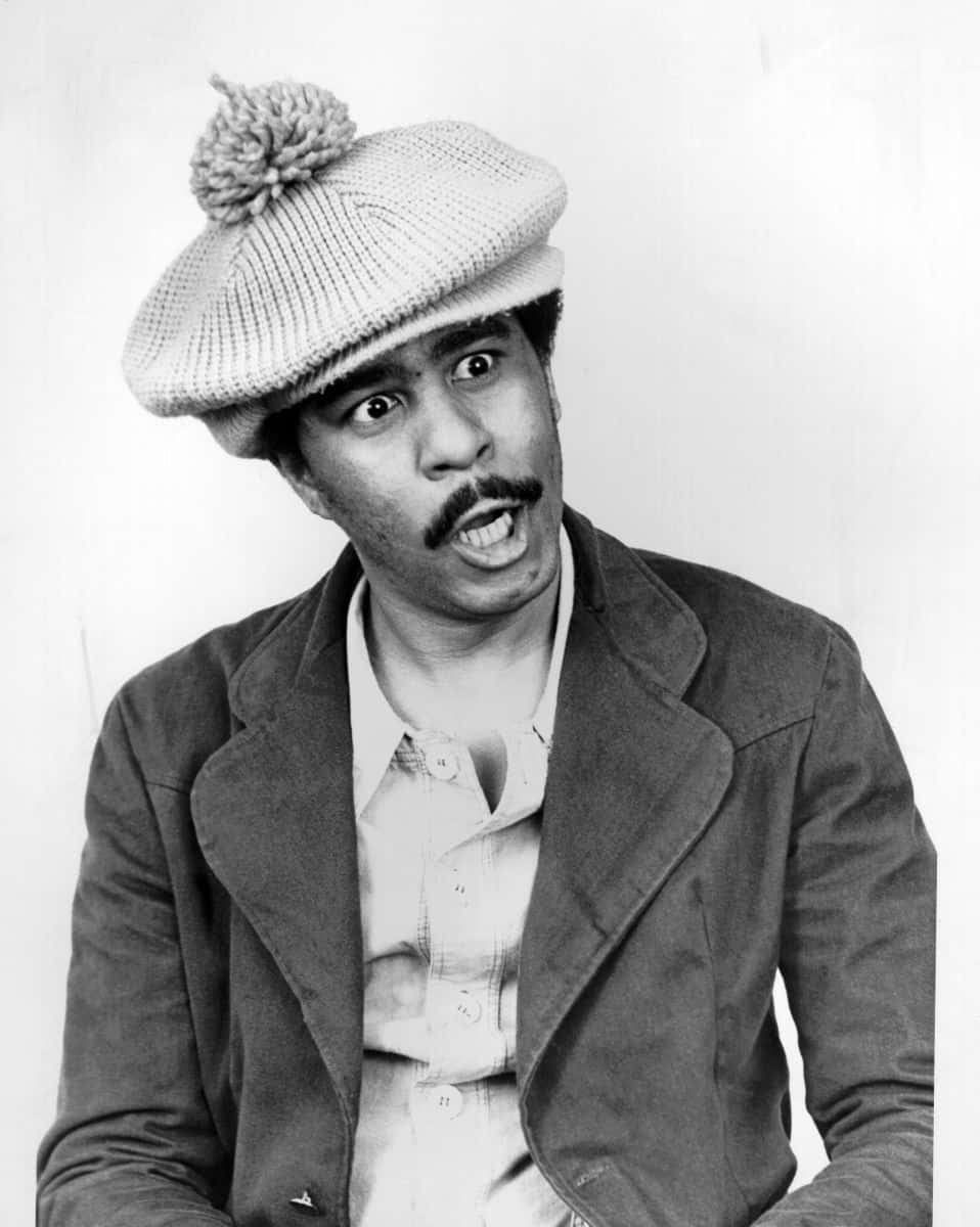 Richard Pryor 桌布 壁紙 — 一個留鬍子、戴針織帽的男人在黑白工作室肖像中做出驚訝的表情。