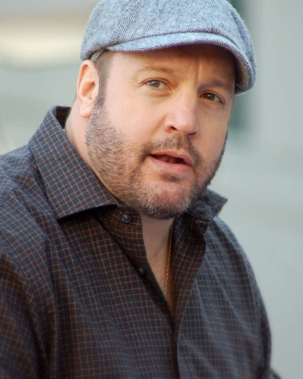 Kevin James 桌布 壁紙 — 一個留鬍鬚、戴灰色平頂帽的男人，穿著格仔恤衫，直視鏡頭。