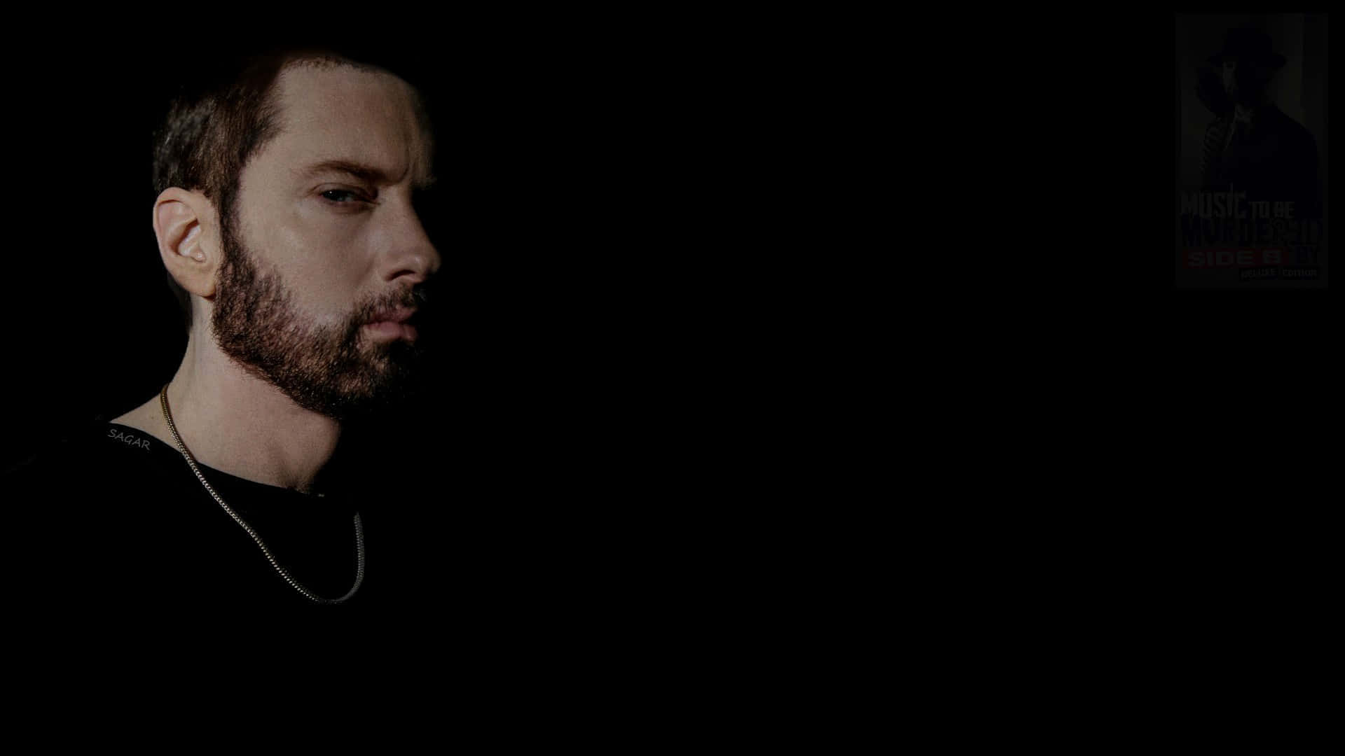 Eminem 桌布 壁紙 — 一個留鬍鬚、戴鏈條頸鏈嘅男人喺昏暗燈光下，喺黑色背景同模糊海報前專注地凝視。