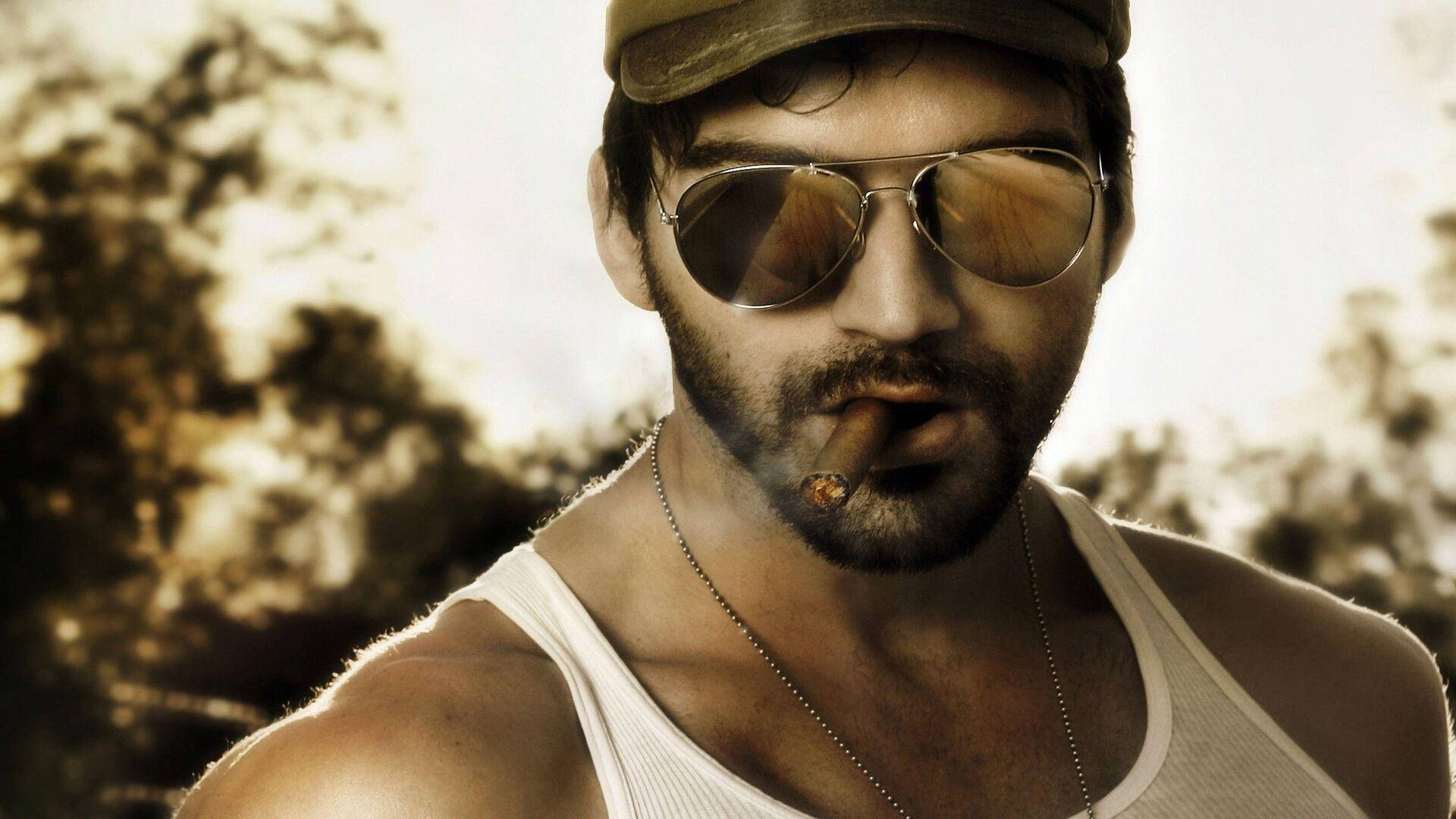 Bollywood HD 桌布 壁紙 — 一個留鬍鬚、戴飛行員太陽眼鏡的男人，戴著帽子和背心，在陽光普照的模糊背景下抽雪茄。