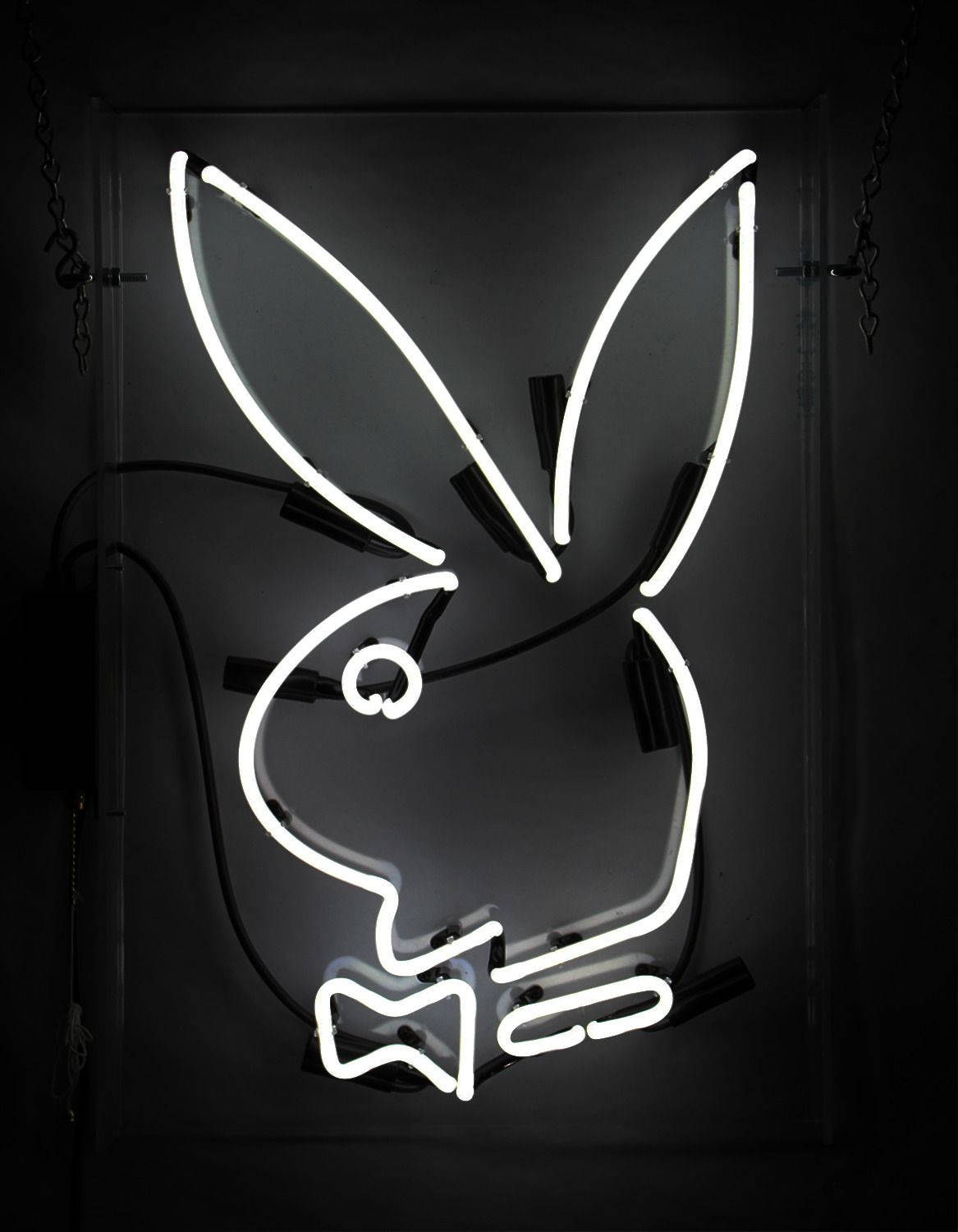 Logo 桌布 壁紙 — 一個發光白色兔仔形狀的霓虹燈牌，帶有蝴蝶結，在深色牆壁上顯現輪廓，牆上可見電線和鏈條。