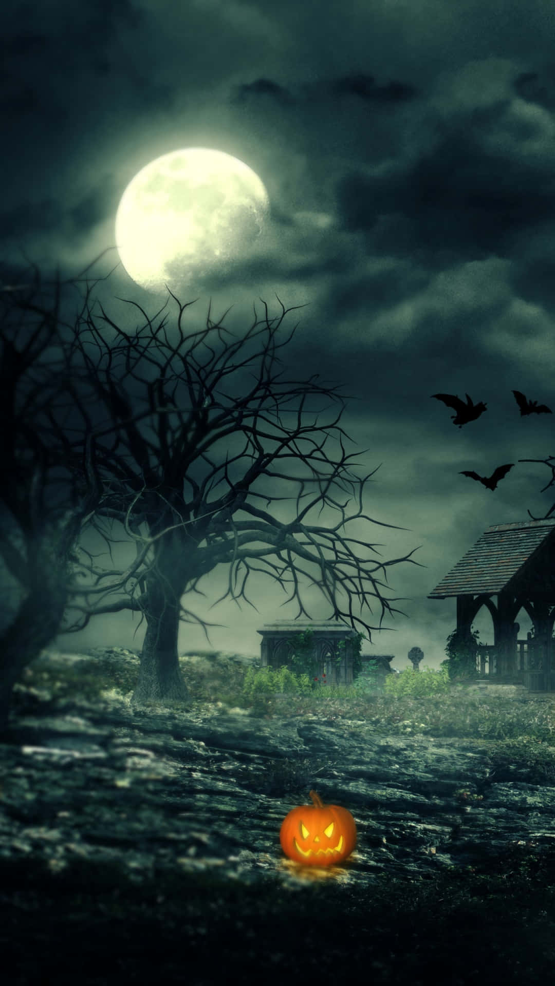 Halloween Phone 桌布 壁紙 — 一個發光的傑克南瓜燈放在霧氣瀰漫的墓園中，滿月下蝙蝠在光禿的樹木附近飛翔。