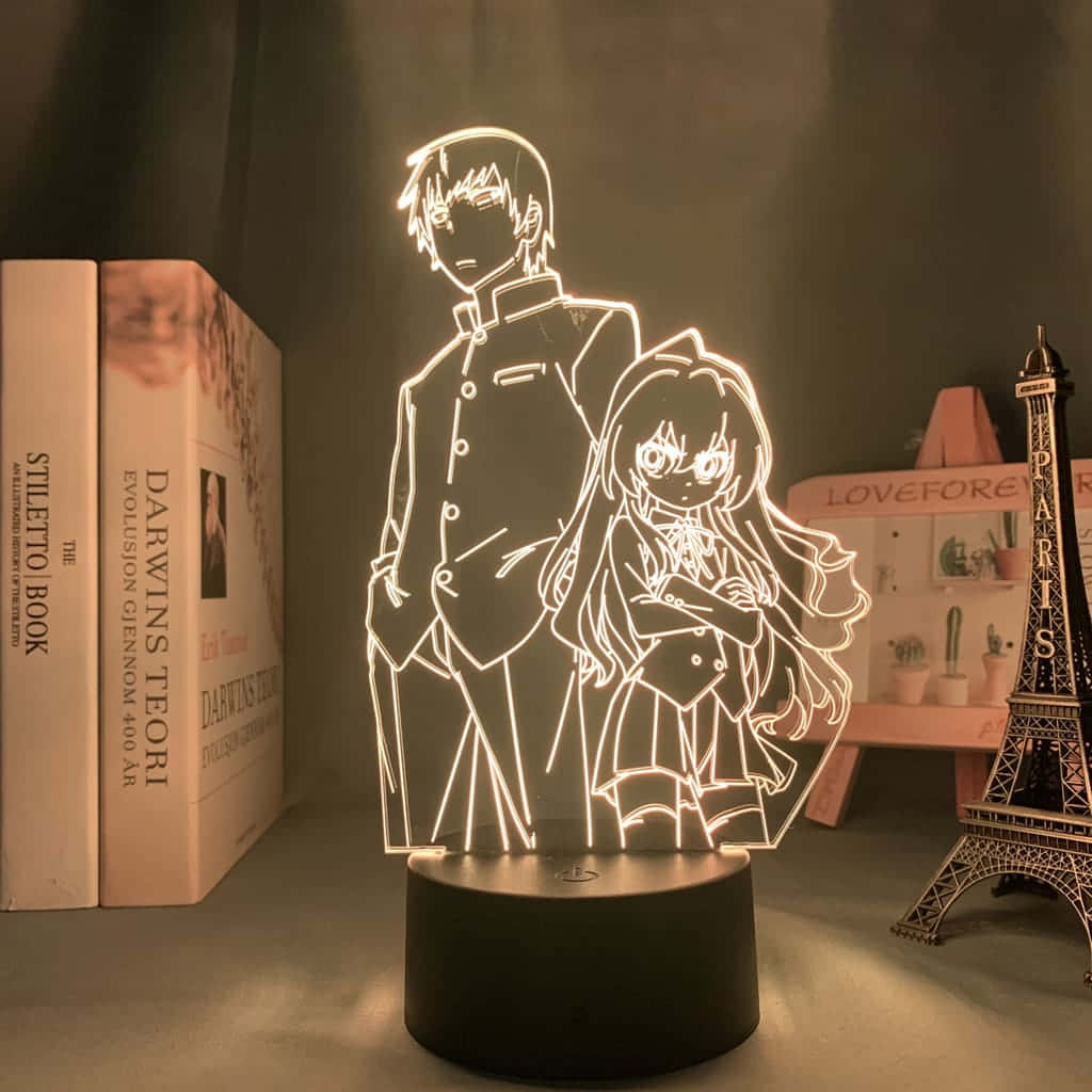 Ryuuji Takasu 桌布 壁紙 — 一個發光的動漫風格3D燈描繪了一個男孩和一個女孩在書桌上靠近書本和一個微型艾菲爾鐵塔站在一起。